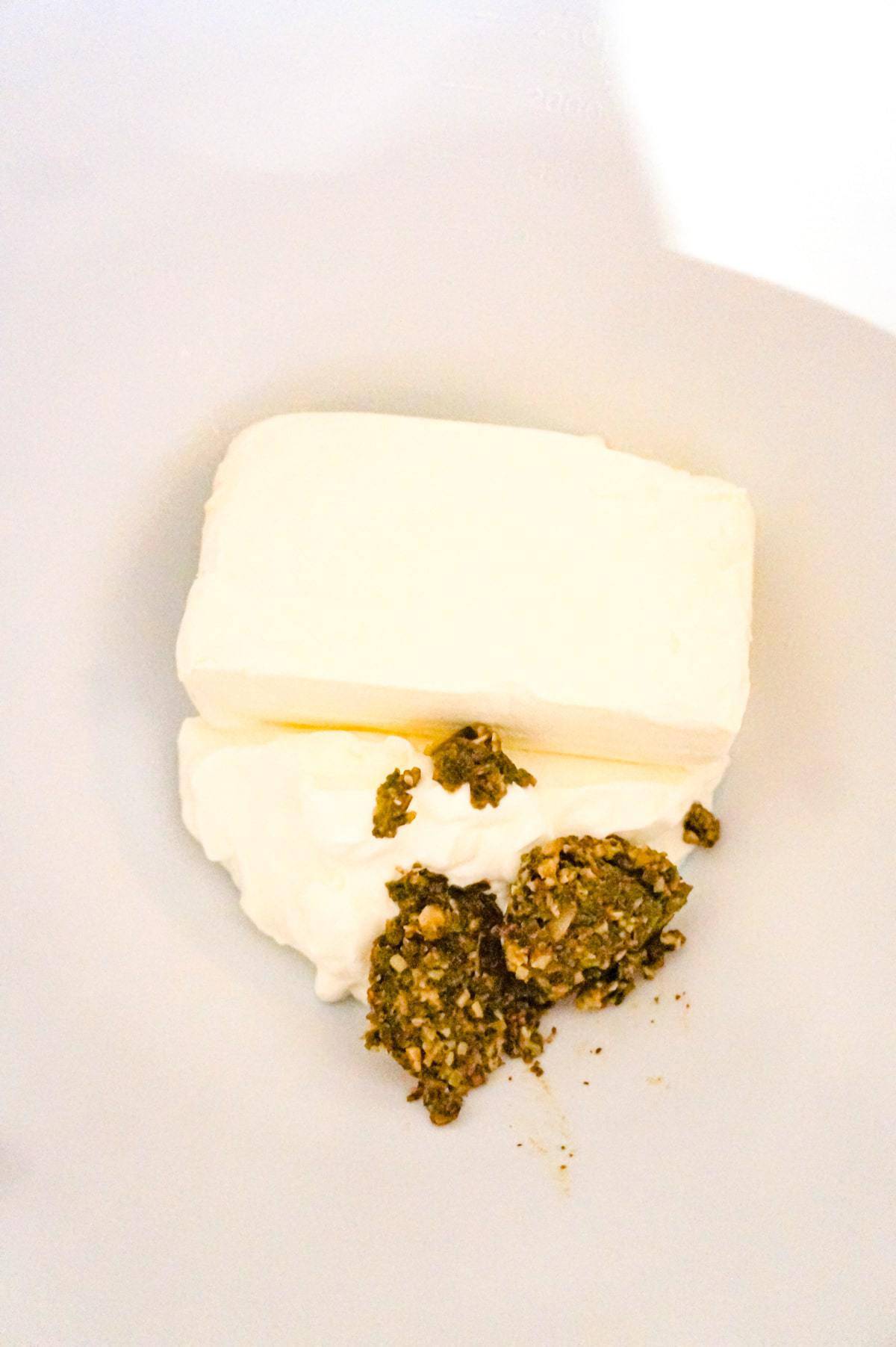 cream cheese, sour cream and basil pesto in a mixing bowl