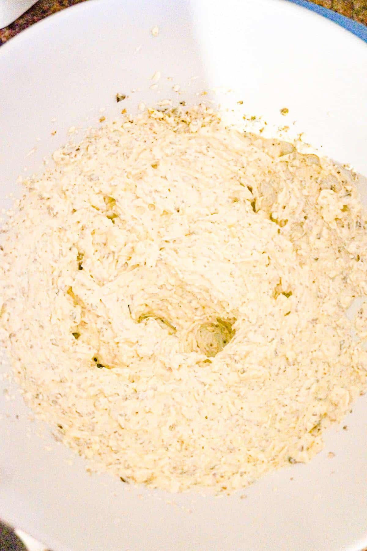 sour cream, cream cheese and basil pesto creamed together in a mixing bowl