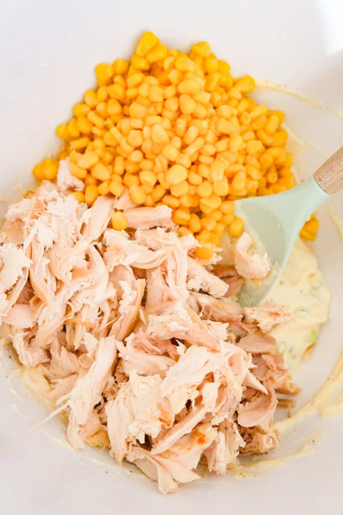shredded chicken and corn on top of cream of chicken soup mixture in a mixing bowl