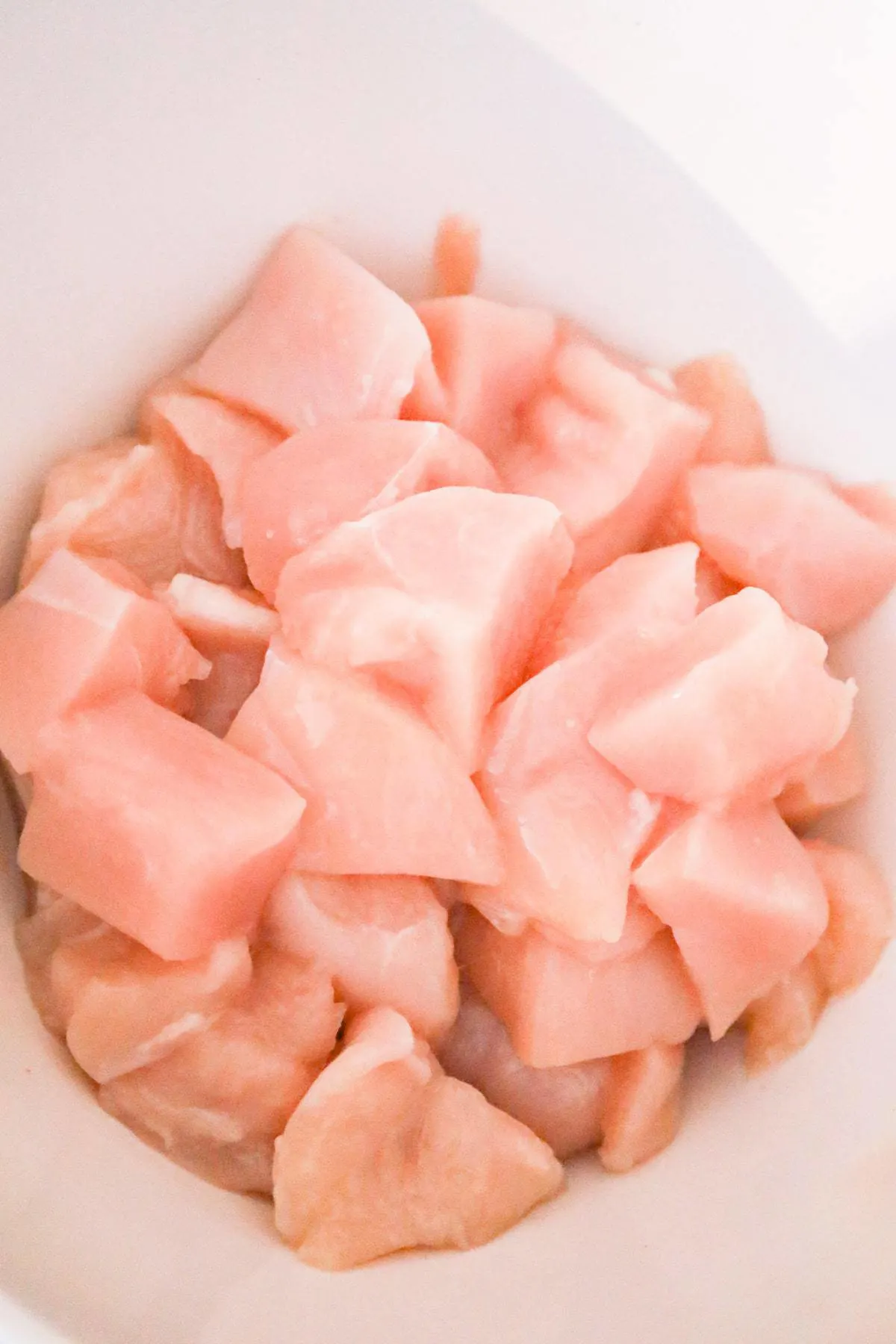raw chicken breast chunks in a mixing bowl