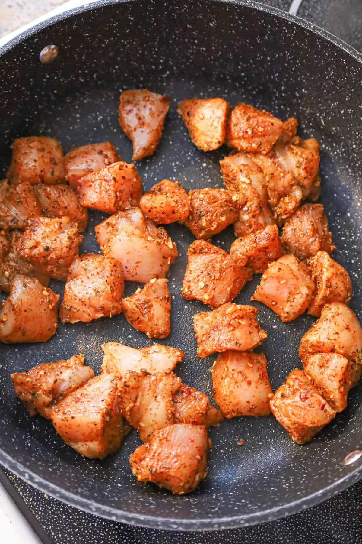 chicken chunks coated in cajun seasoning in a saute pan