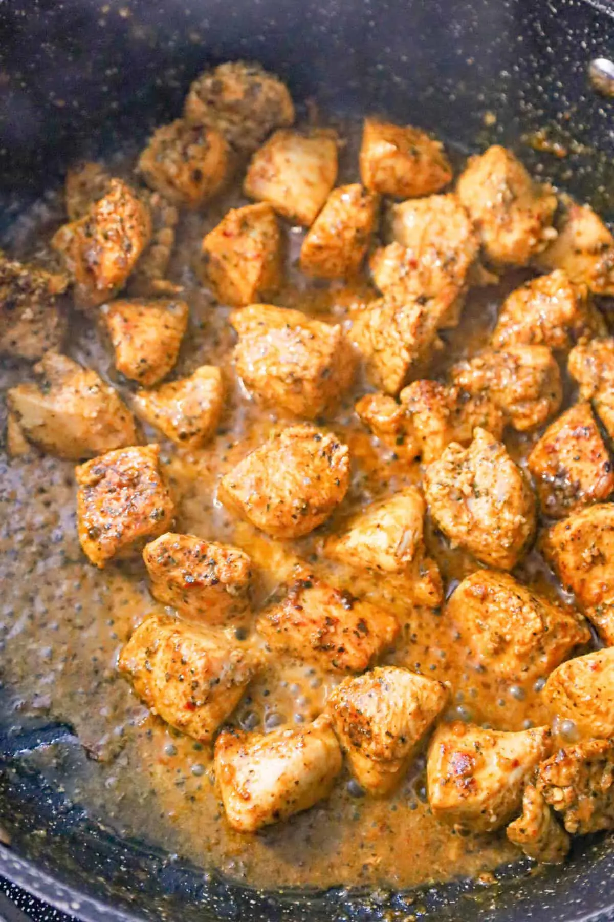 melted butter and cajun chicken chunks in a saute pan