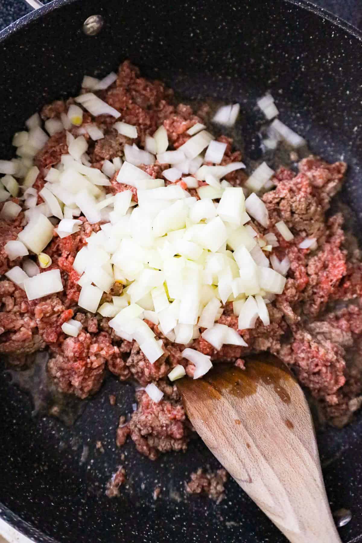 diced onions on top of ground cooking in a saute pan