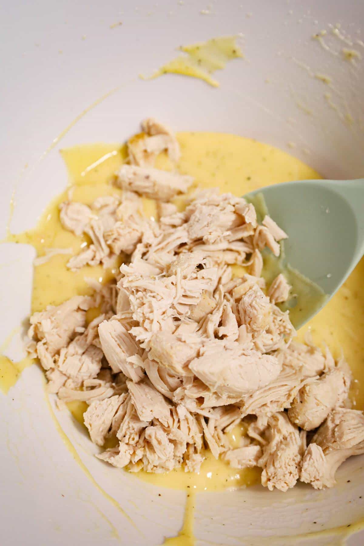 cooked, chopped chicken on top of cream of chicken soup in a mixing bowl