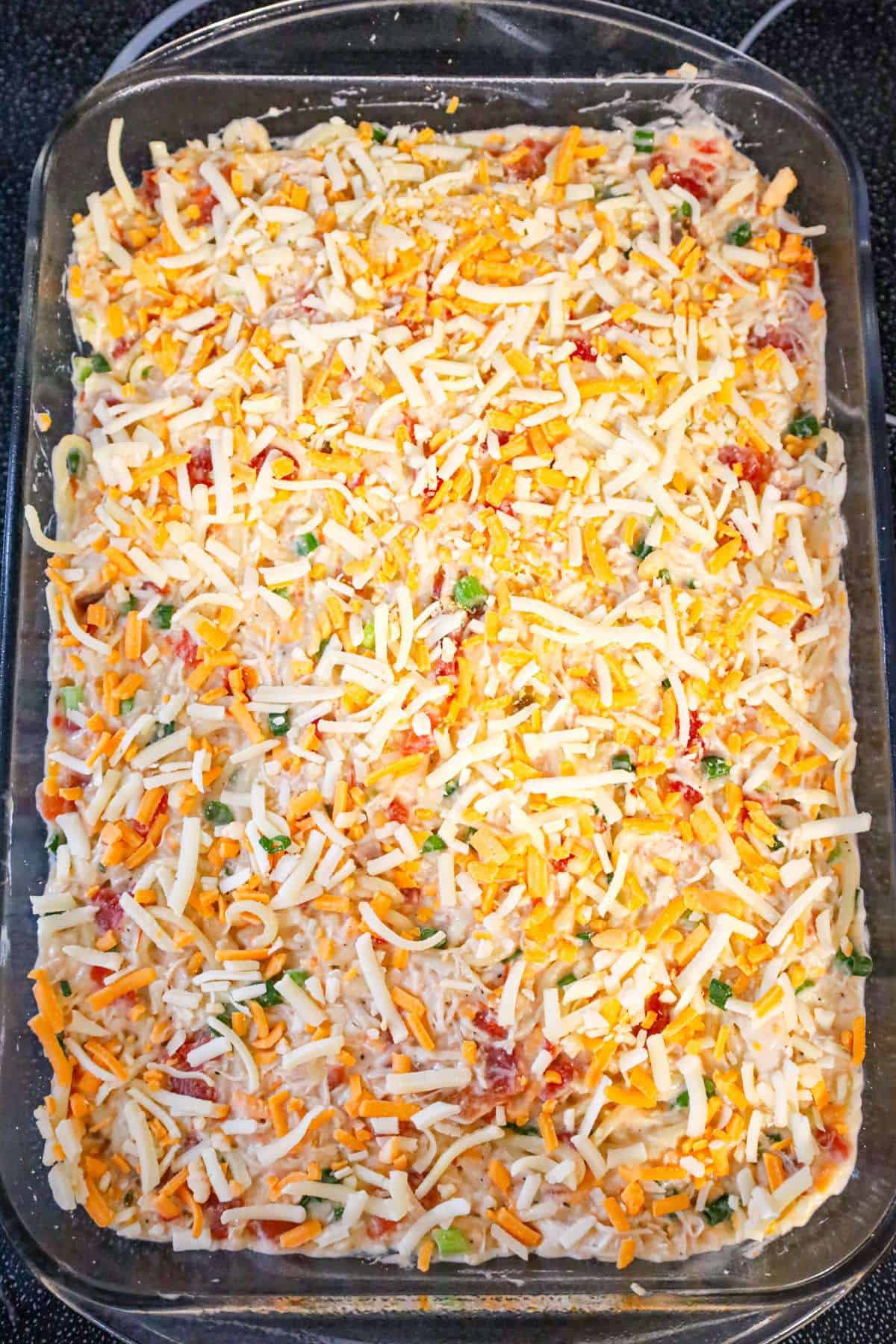 shredded cheese on top of spaghetti with rotel in a baking dish