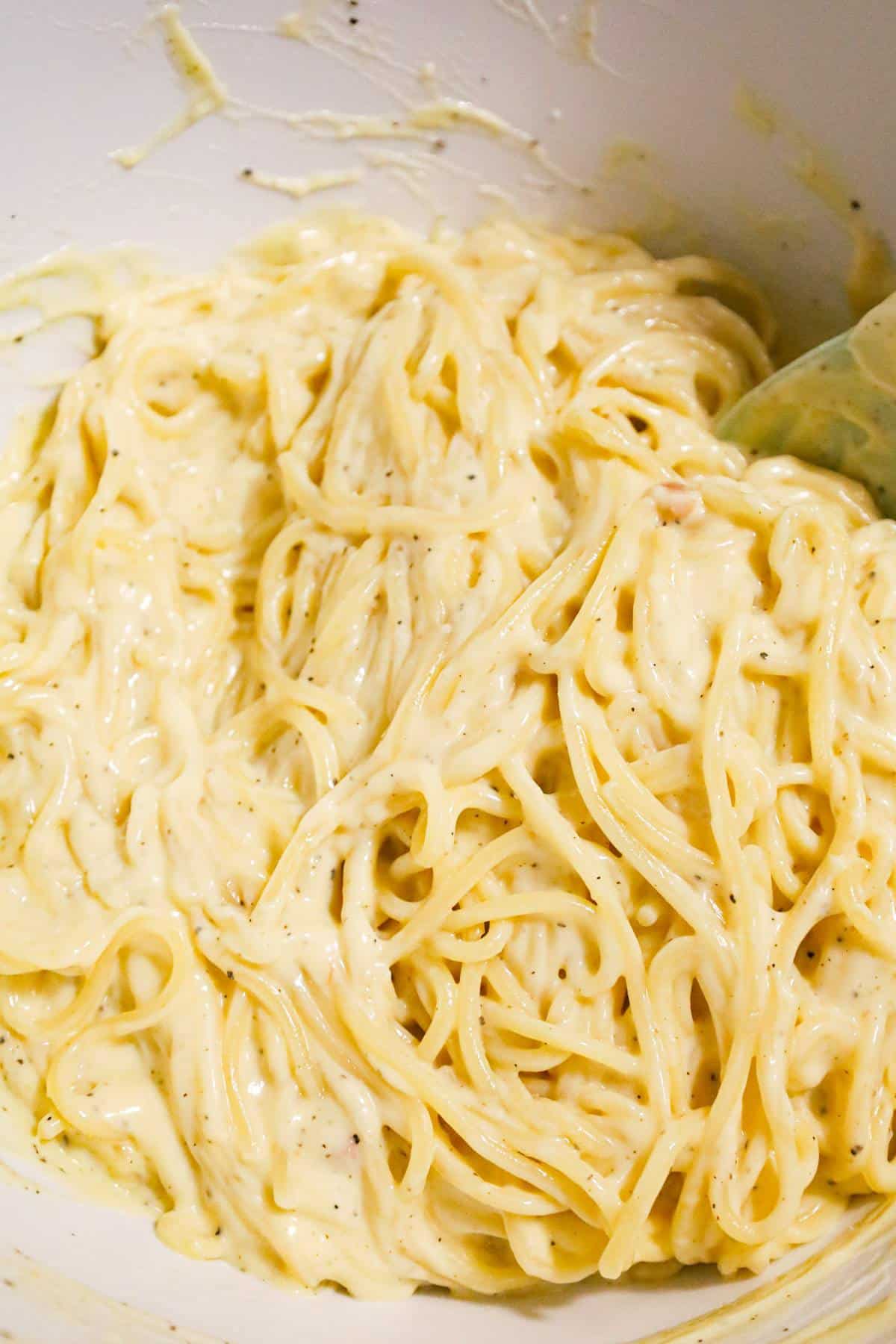 spaghetti in a creamy sauce in a mixing bowl