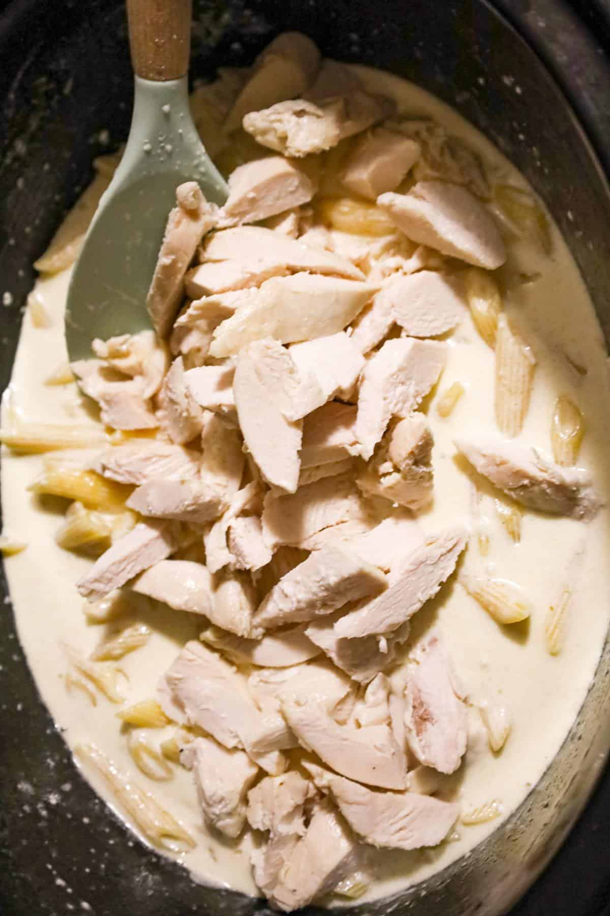 chopped chicken breast on top of penne alfredo in a crock pot