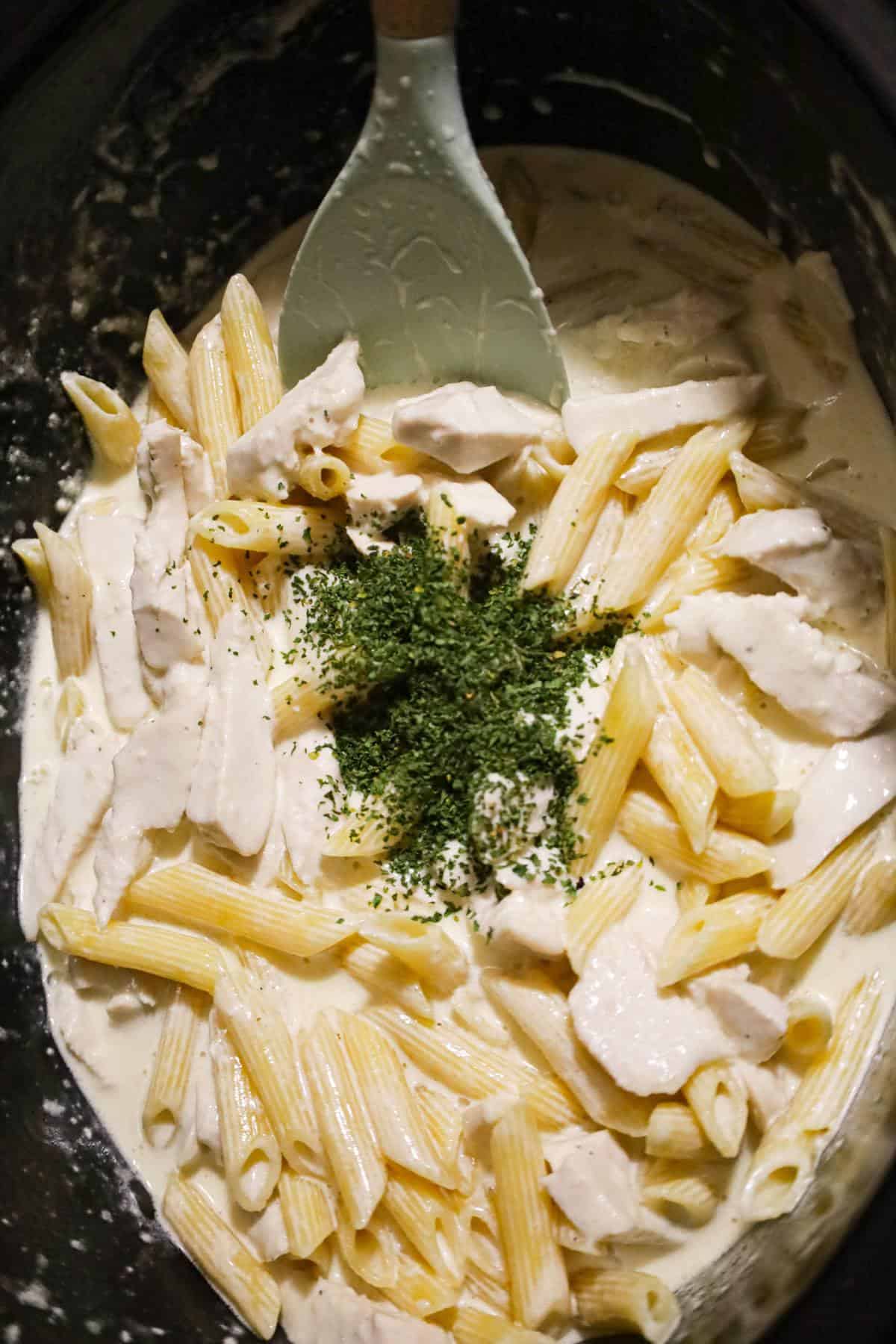 parsley flakes on top of chicken alfredo in a crock pot