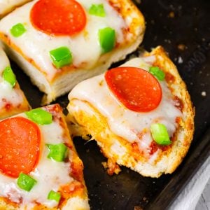 French Bread Pizza is an easy dinner or party snack recipe made with a large loaf of French or Italian bread toasted with garlic butter and topped with pizza sauce, cheese, pepperoni and green peppers.