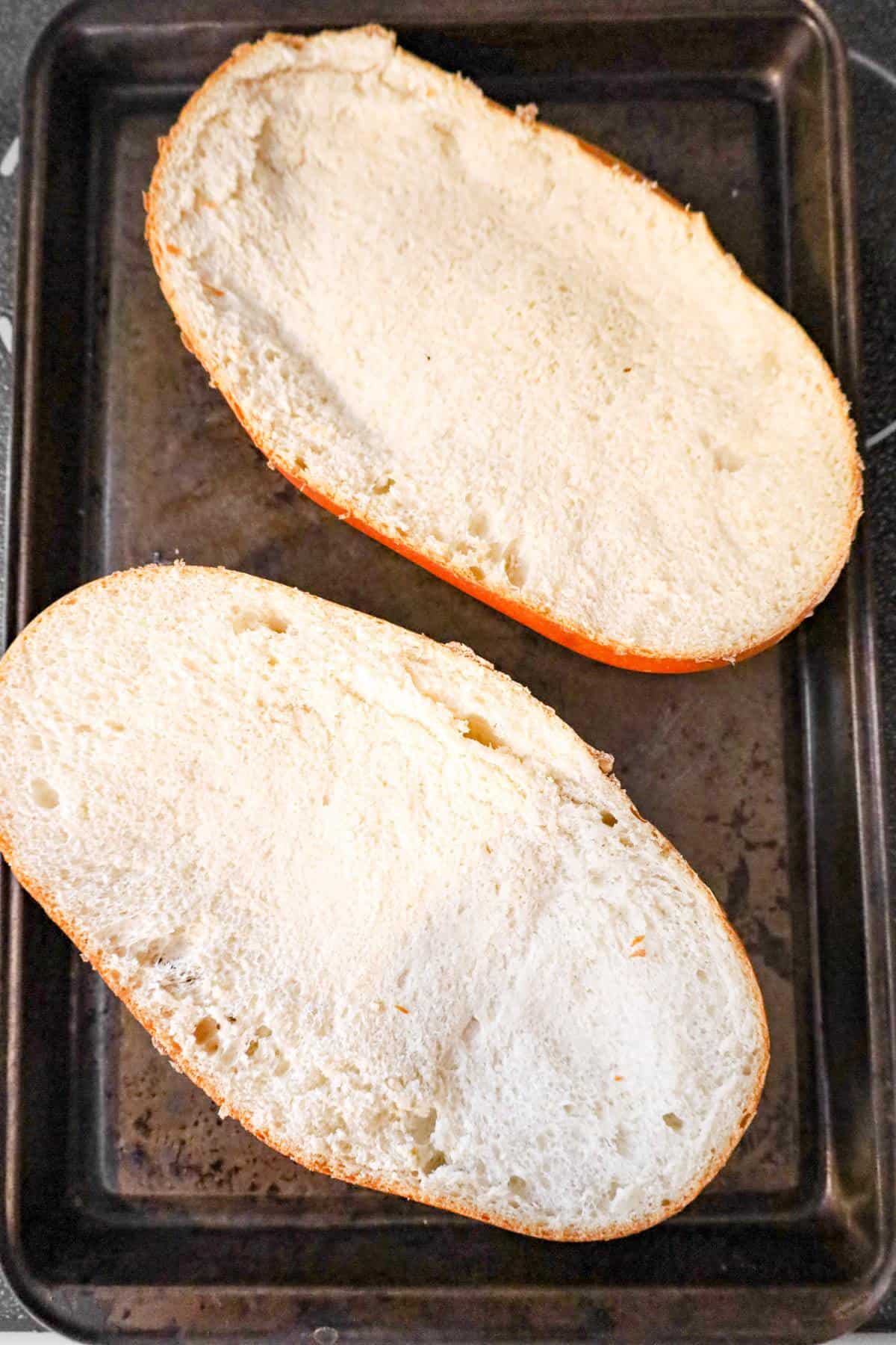 French bread loaf halves on a baking sheet