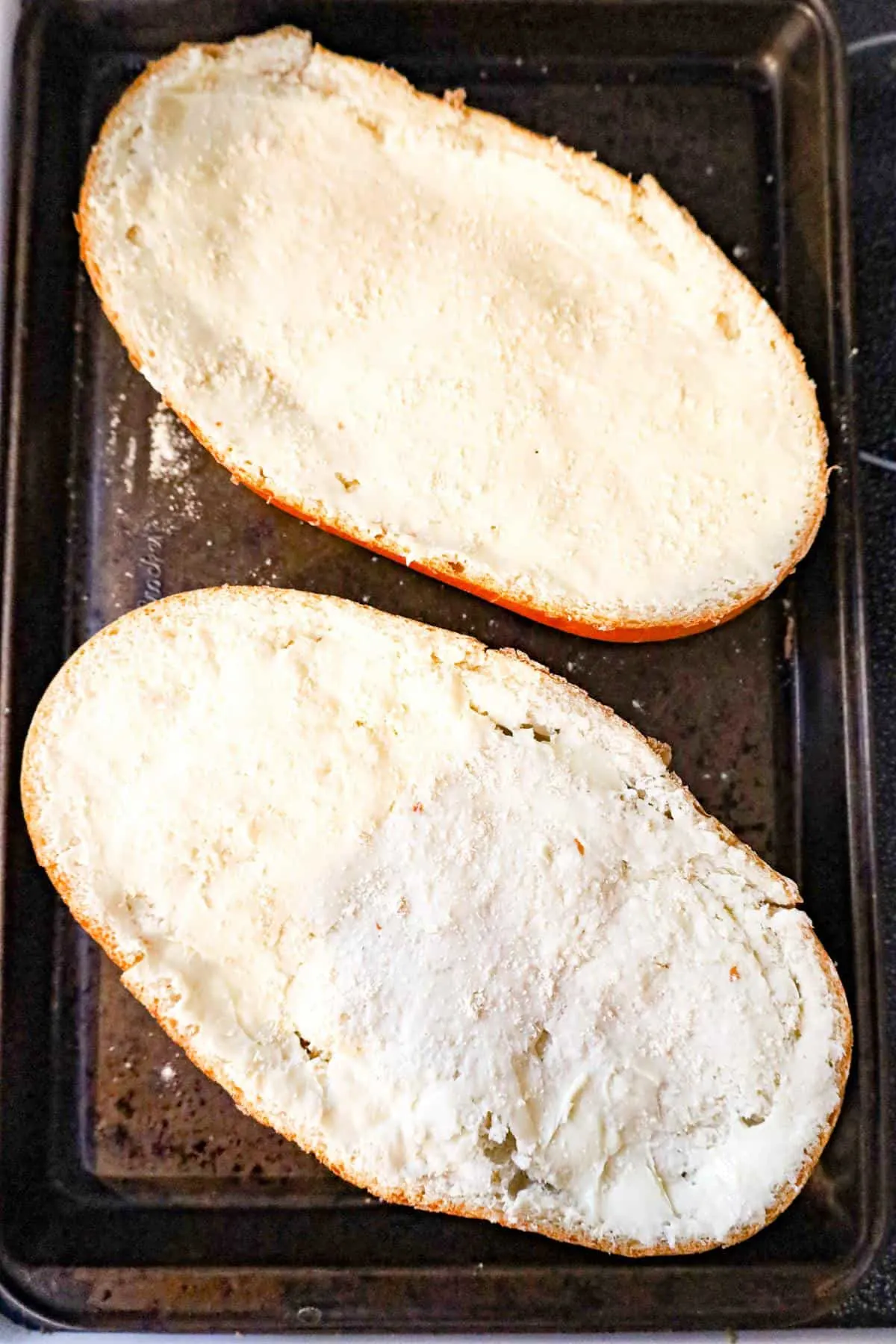 French bread spread with butter and garlic powder on a baking sheet