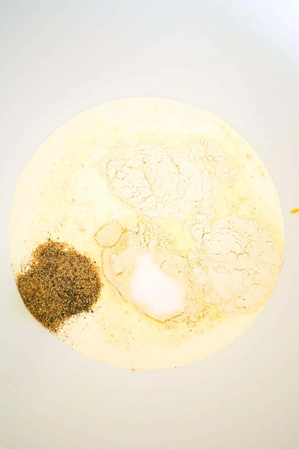 spices on top of heavy cream and cheddar soup in a mixing bowl