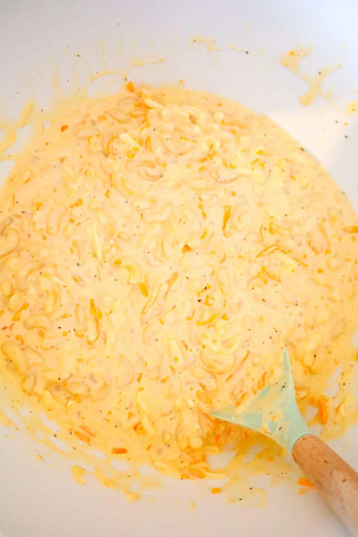 creamy mac and cheese mixture being stirred in a mixing bowl
