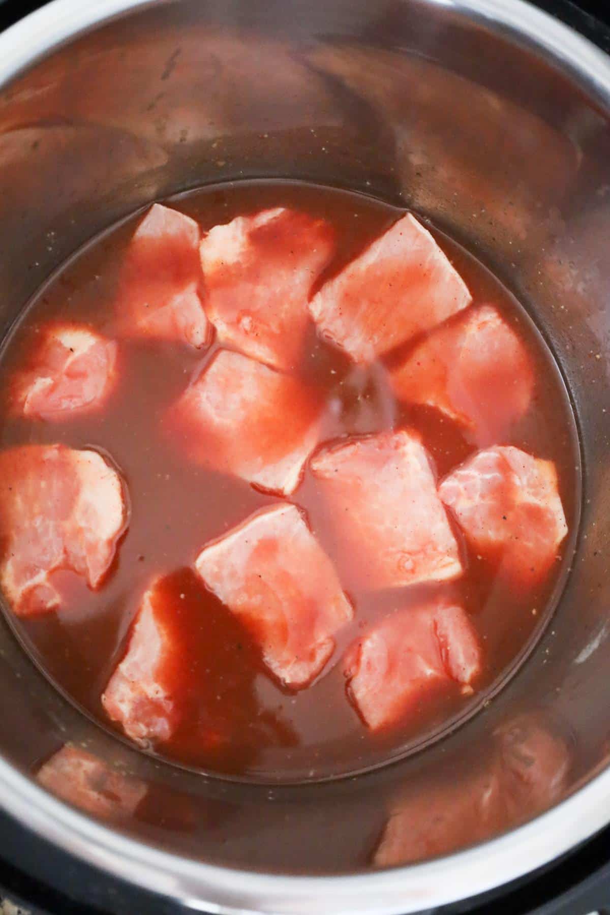 raw pork roast chunks in liquid in an Instant Pot
