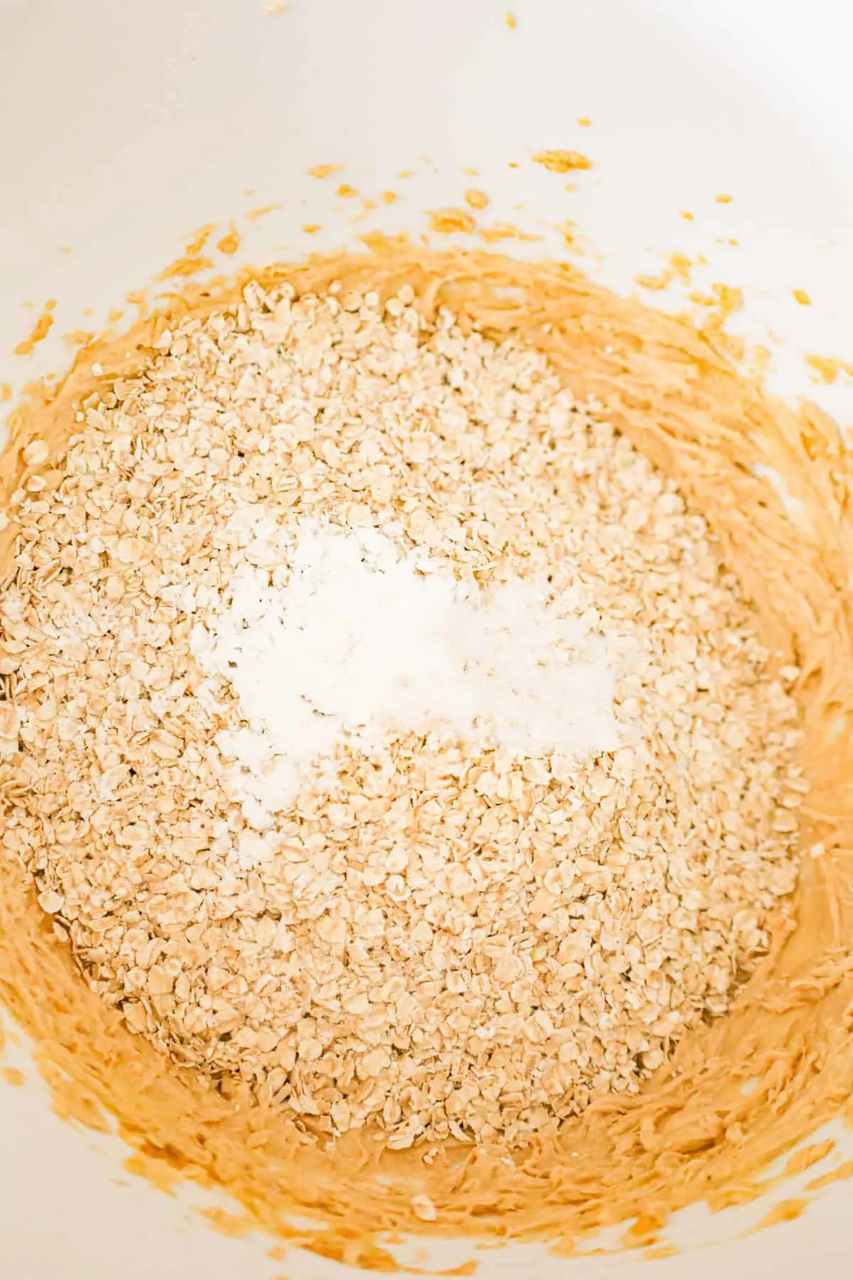 baking powder, salt and quick oats on top of creamy peanut butter mixture in a mixing bowl