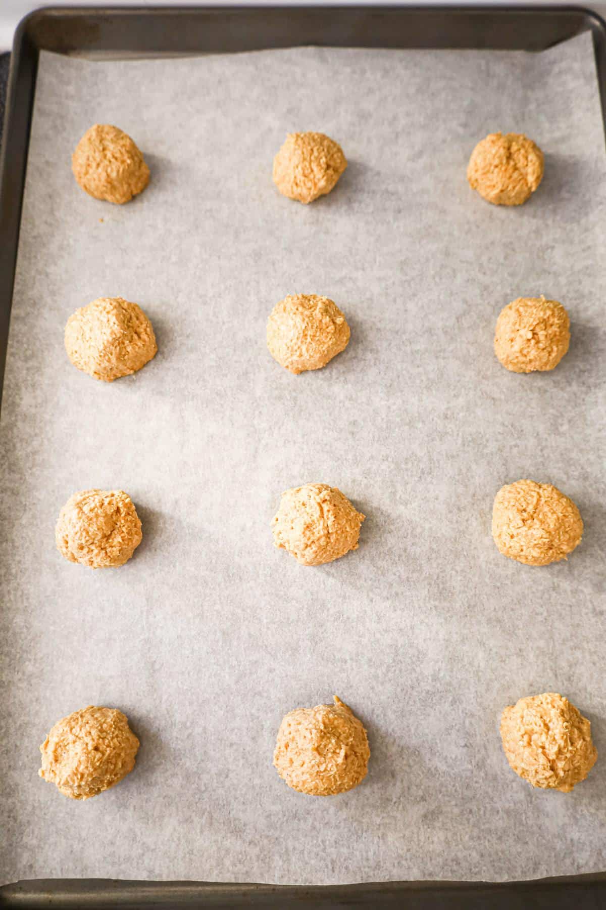 peanut butter oatmeal cookie dough balls on a parchment lined baking sheet