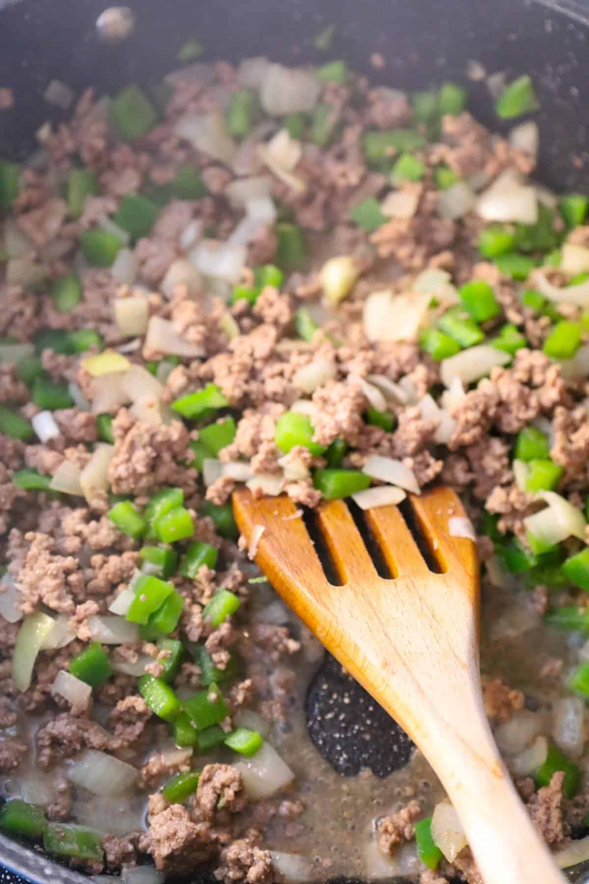 ground beef and diced peppers and onions cooking in a saute pan