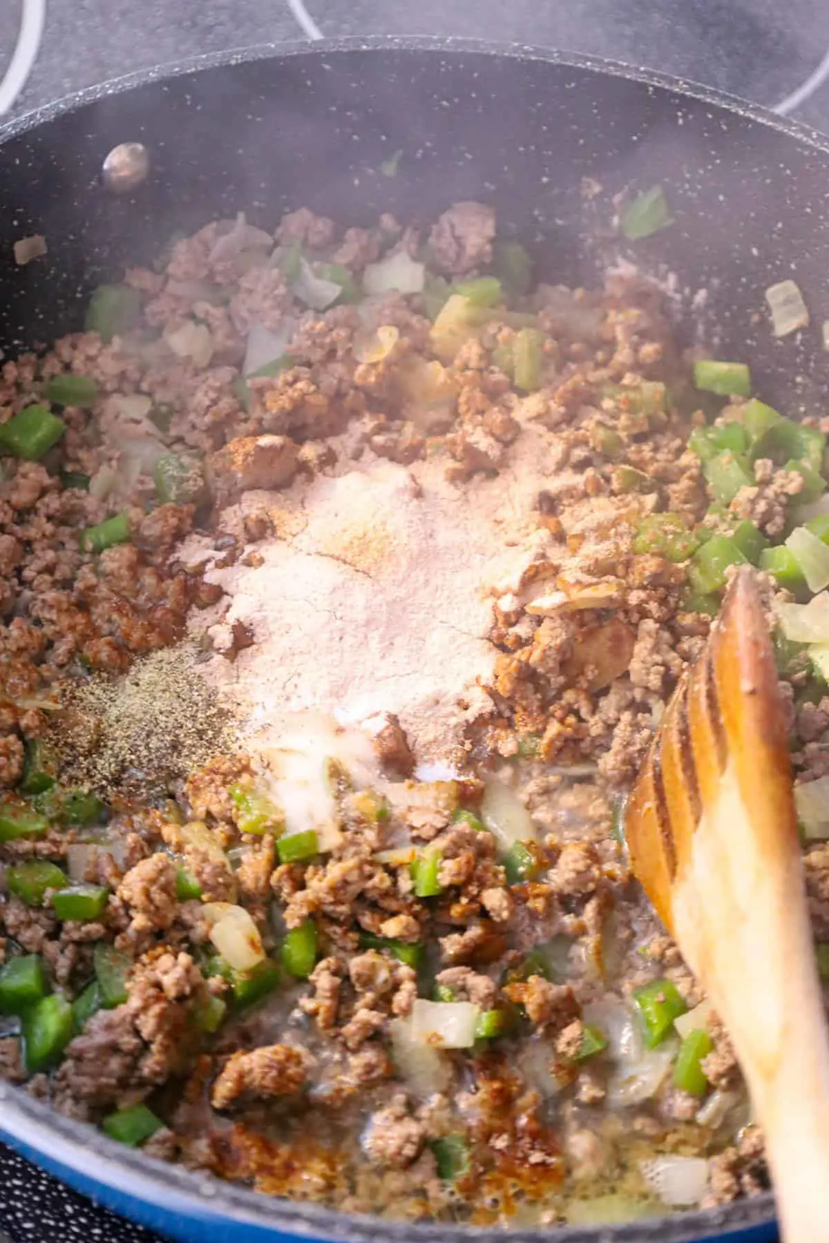 brown gravy mix on top of cooked ground and diced green peppers and diced onions
