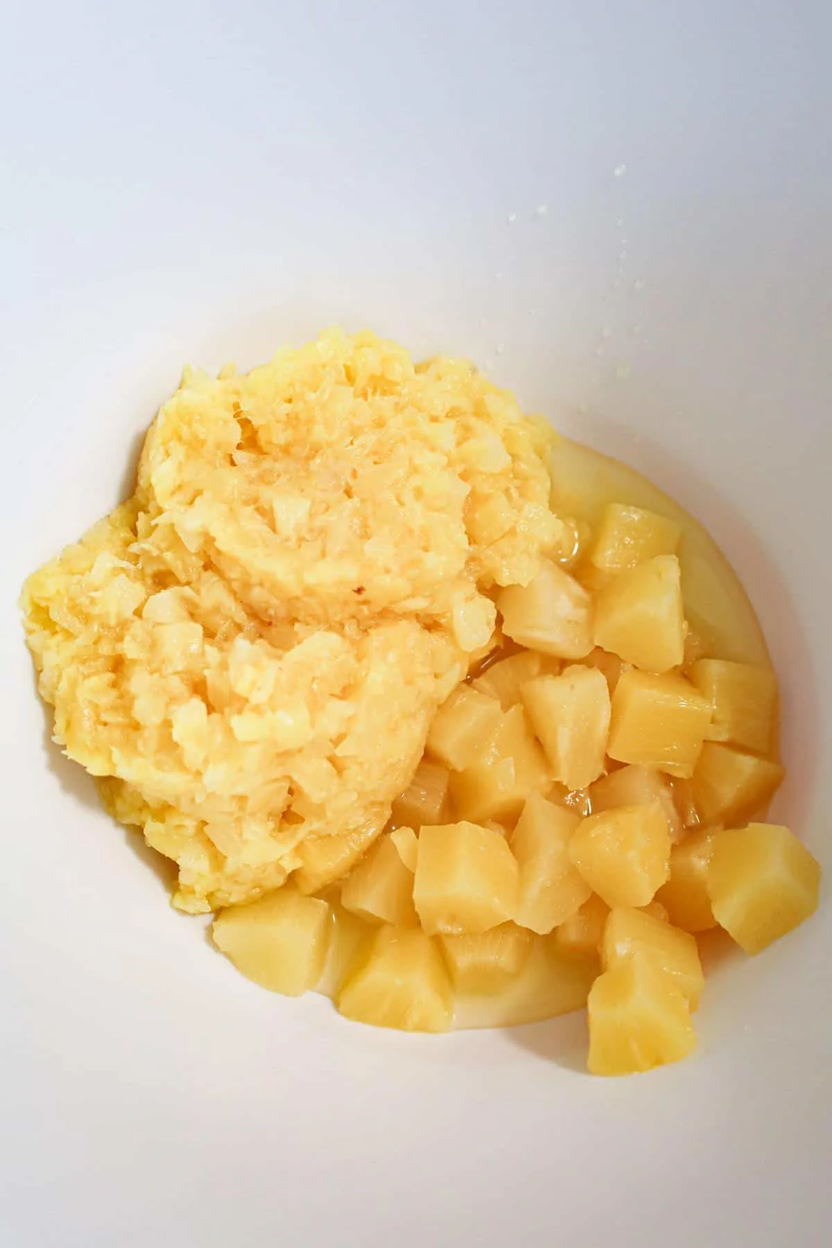 crushed pineapple and pineapple chunks in a mixing bowl