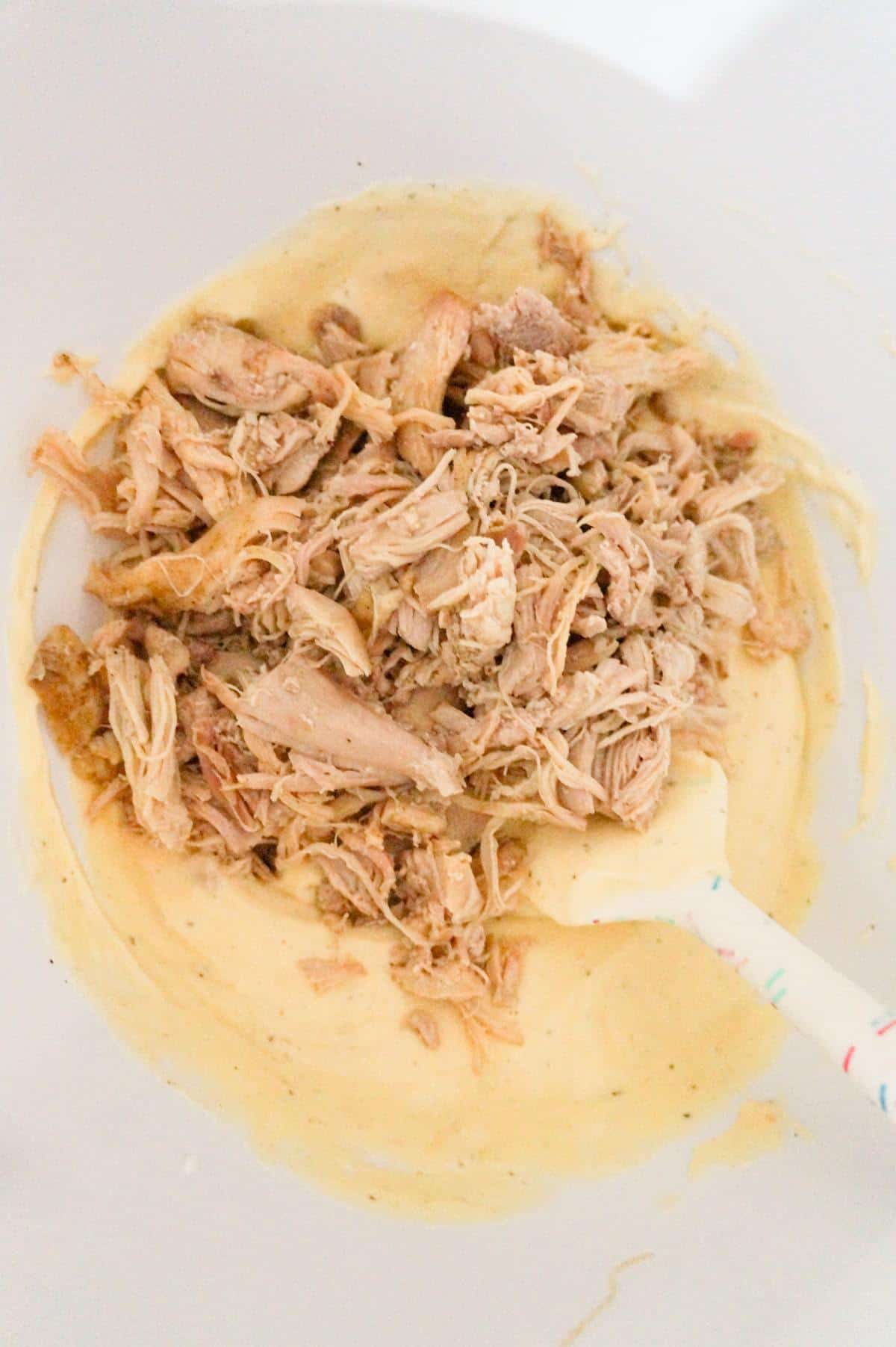 shredded chicken on top of cream of chicken soup in a mixing bowl