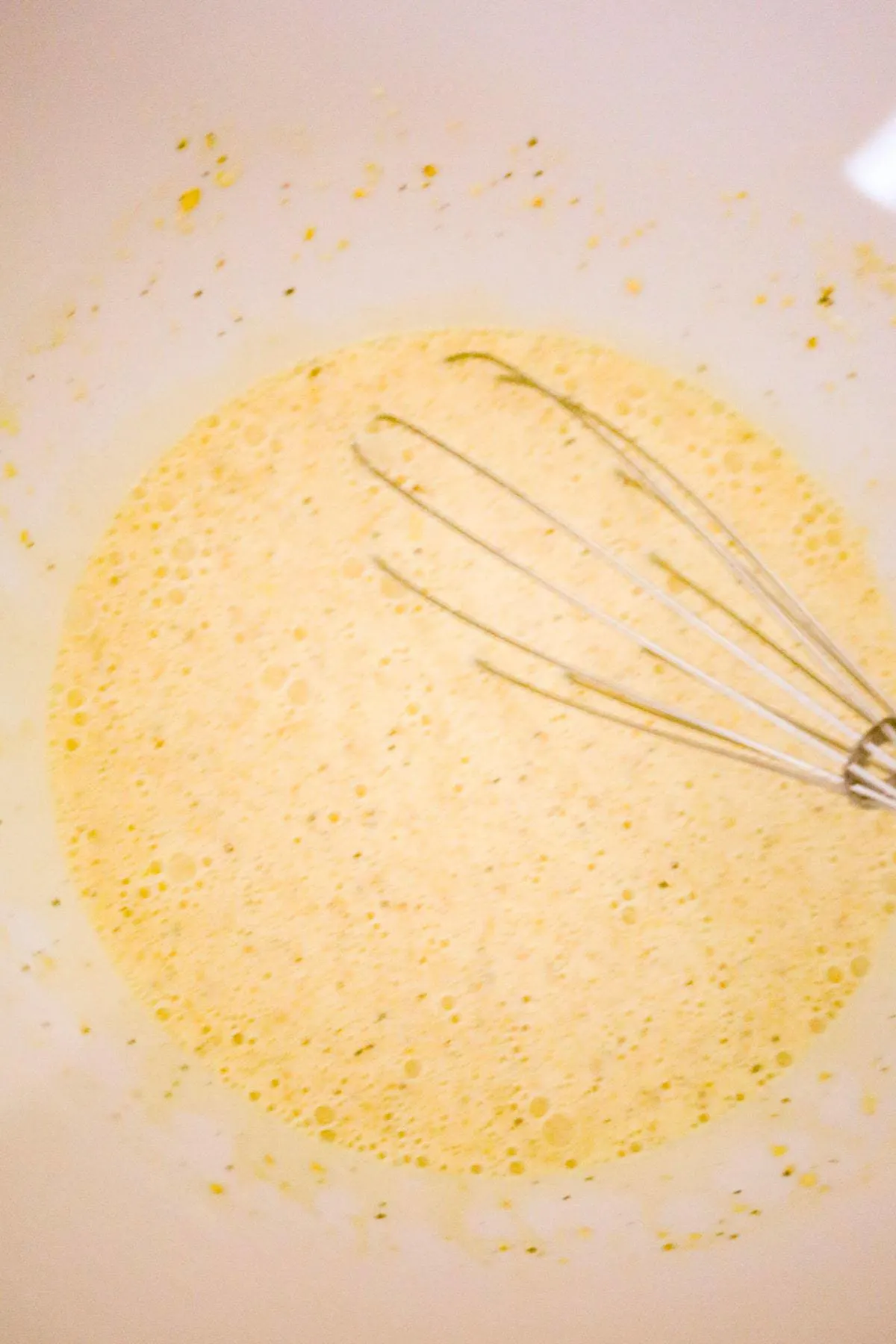 heavy cream, evaporated milk and egg mixture being whisked in a mixing bowl
