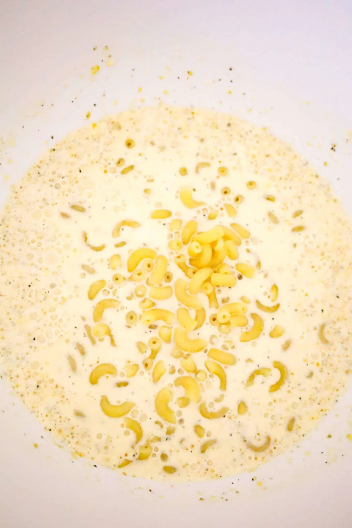 cooked macaroni noodles added to heavy cream and evaporated milk mixture in a mixing bowl