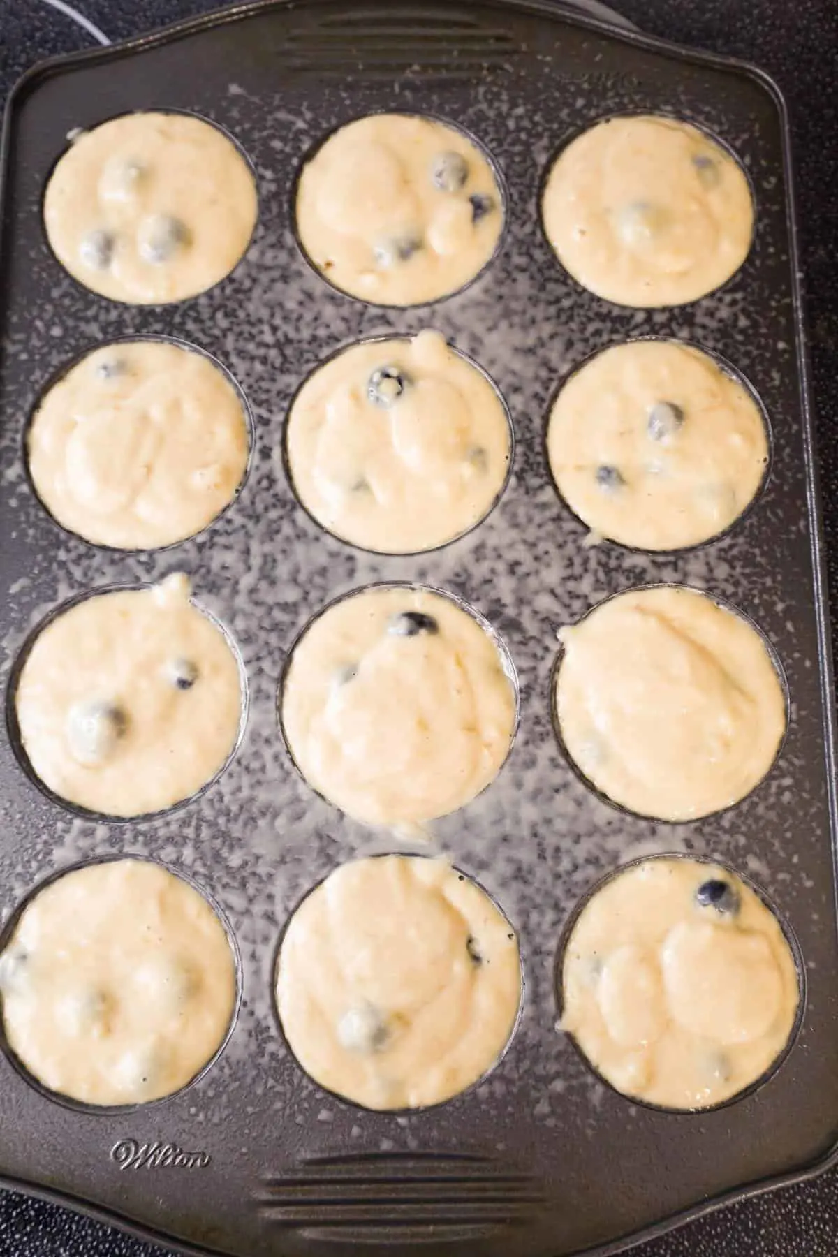 banana blueberry muffin batter in a muffin tin