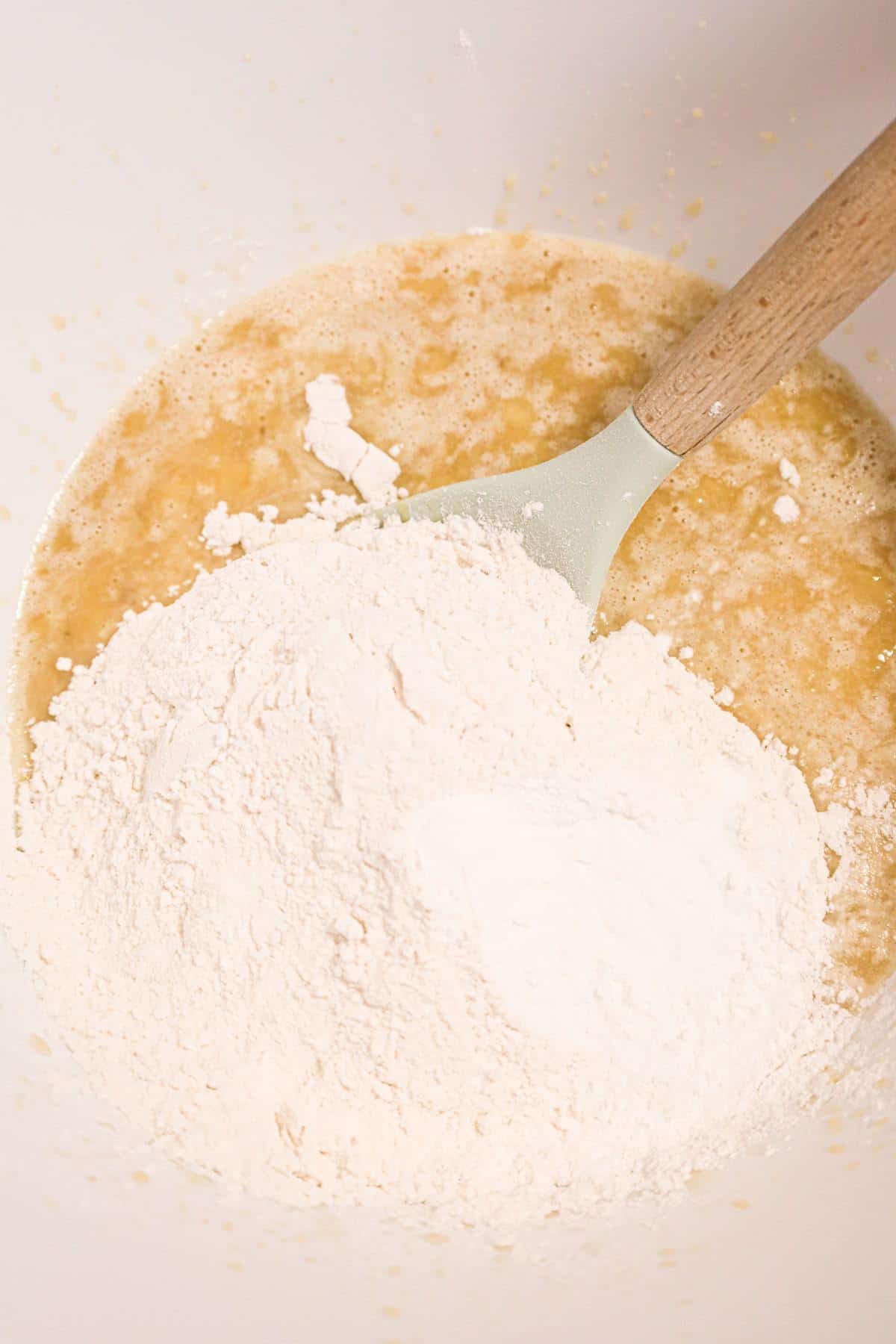 flour on top of banana muffin batter in a mixing bowl