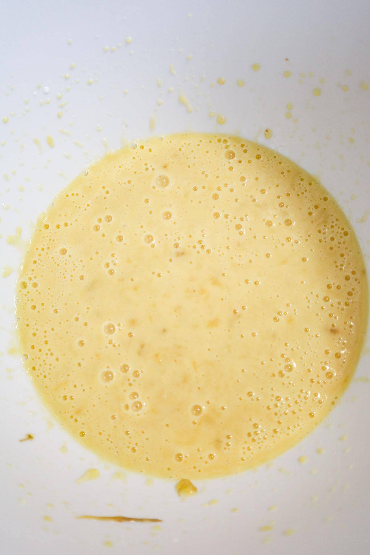 creamy banana, egg, milk and oil mixture in a mixing bowl