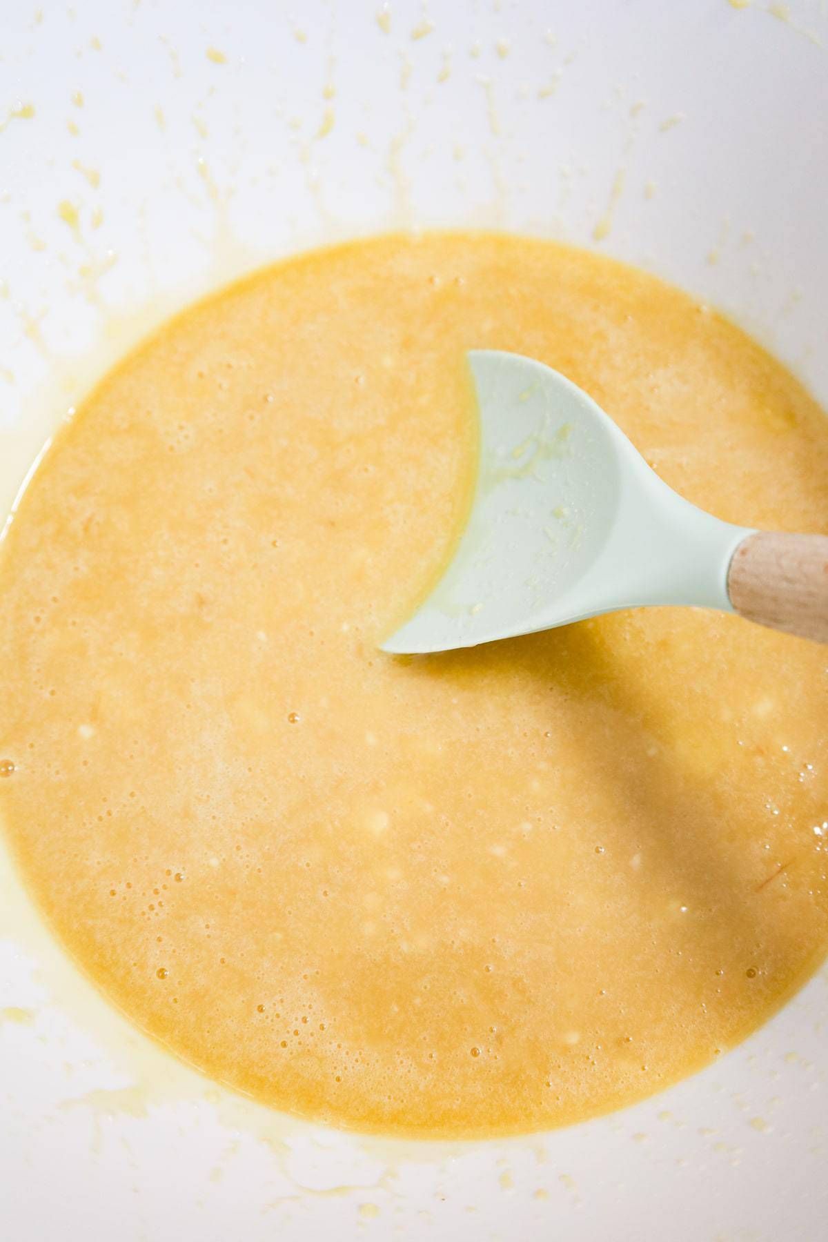 stirring banana muffin batter in a mixing bowl