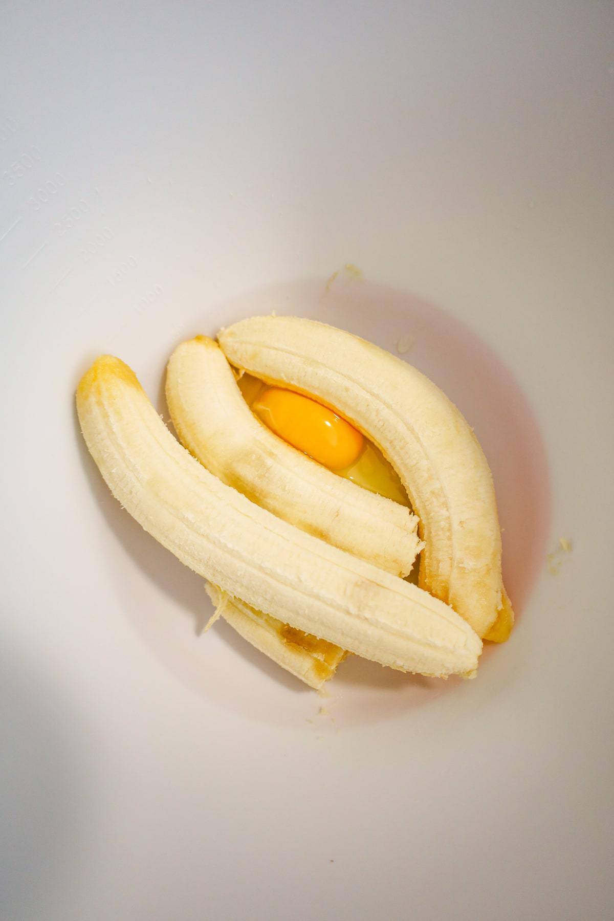 ripe bananas and an egg in a mixing bowl