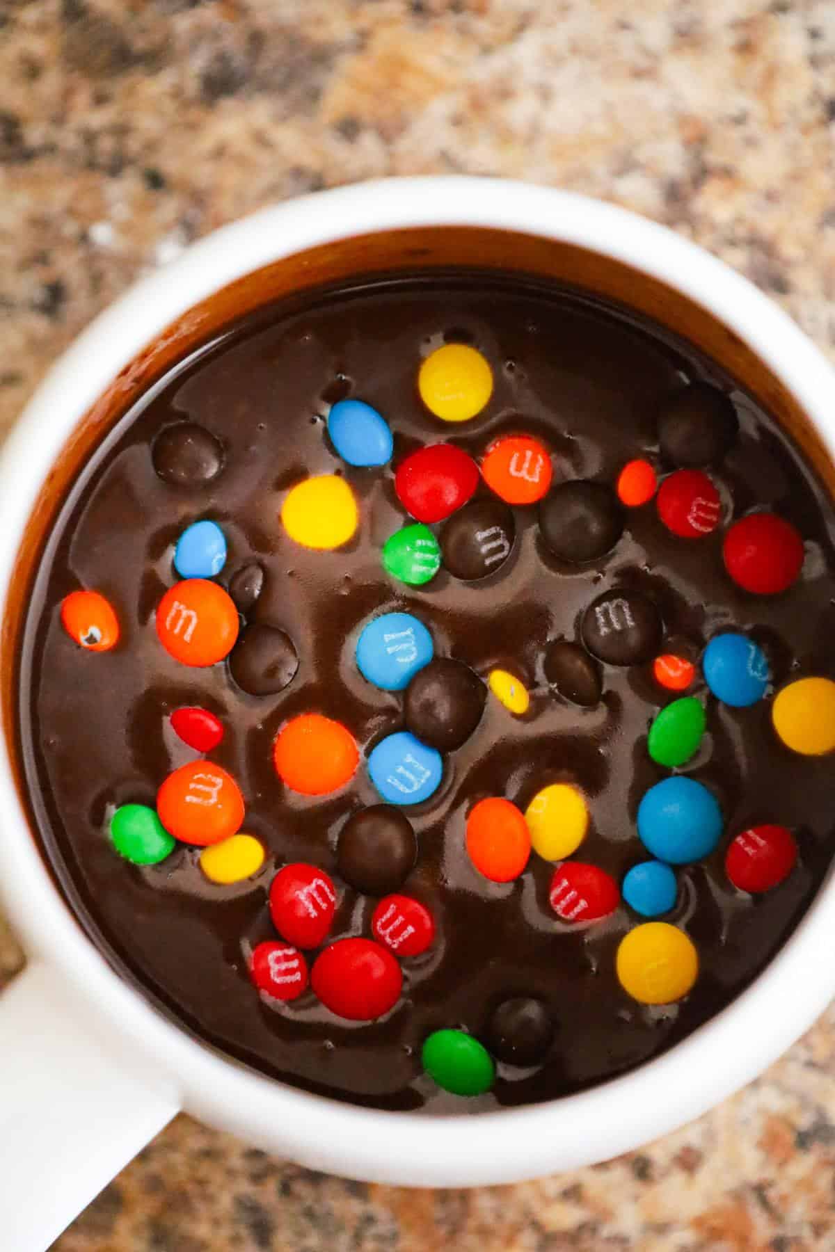 mini M&Ms on top of brownie batter in a mug