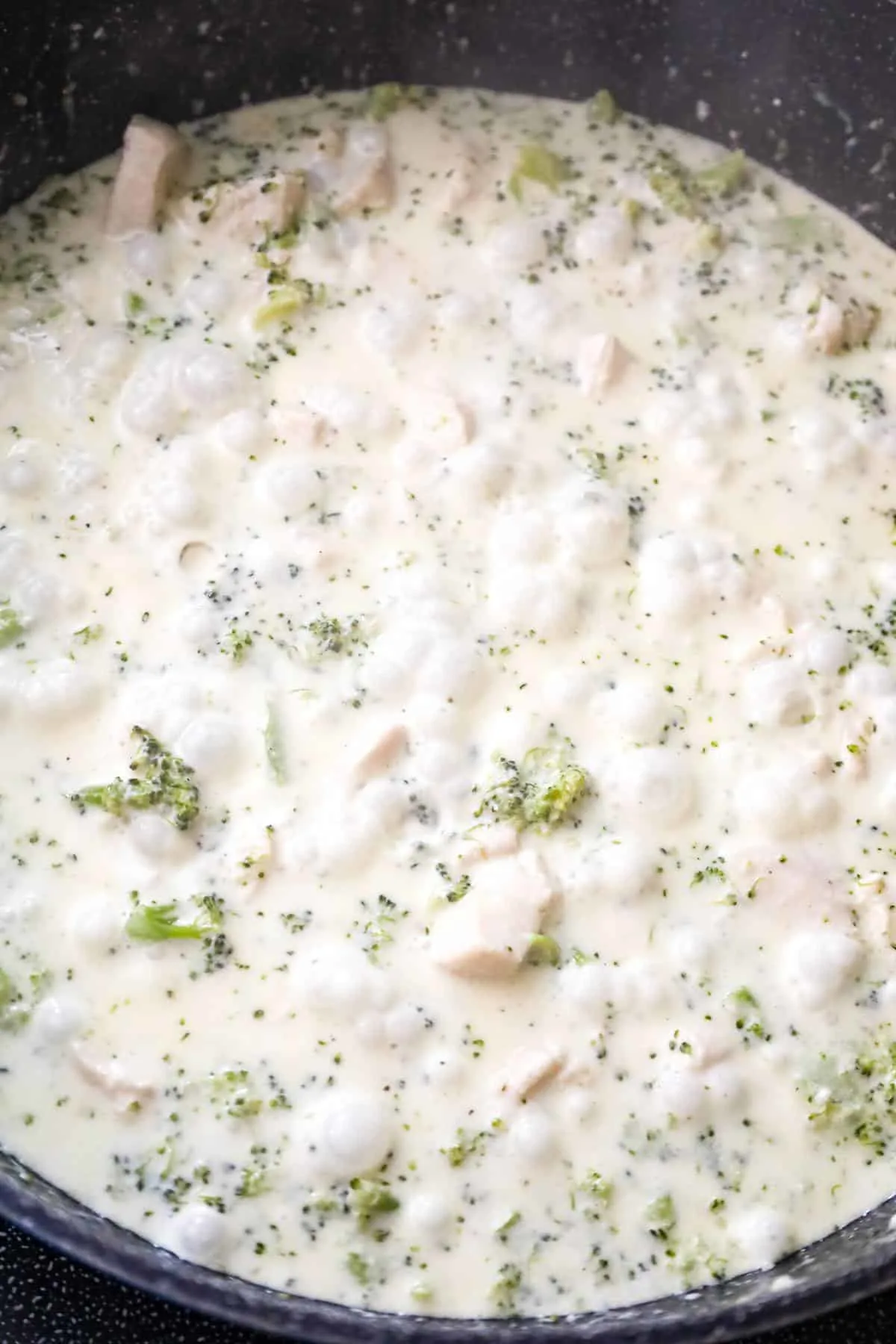 creamy broccoli alfredo sauce cooking in a saute pan