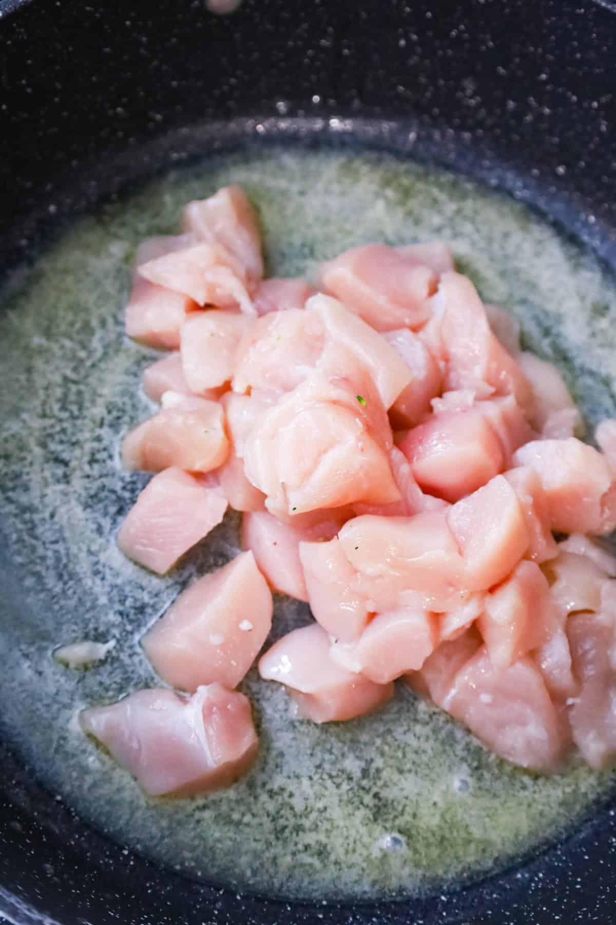 raw chicken breast chunks in a saute pan