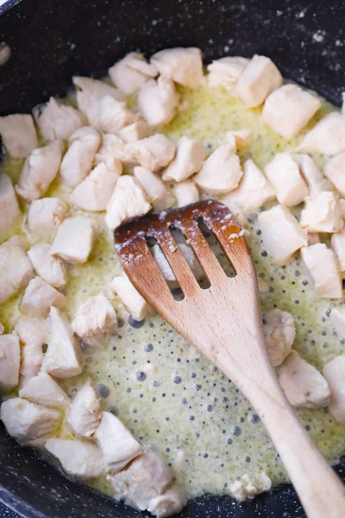 chicken breast chunks cooking in butter in a saute pan