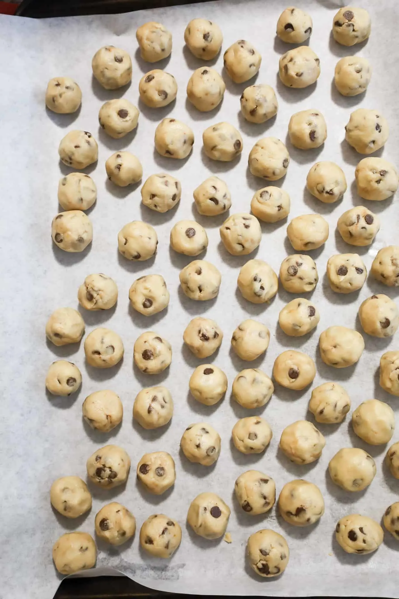 mini cookie dough balls on a parchment lined baking sheet