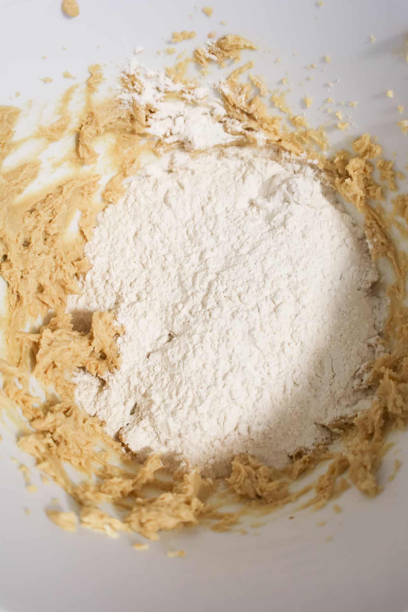 all purpose flour on top of cookie dough mixture in a mixing bowl