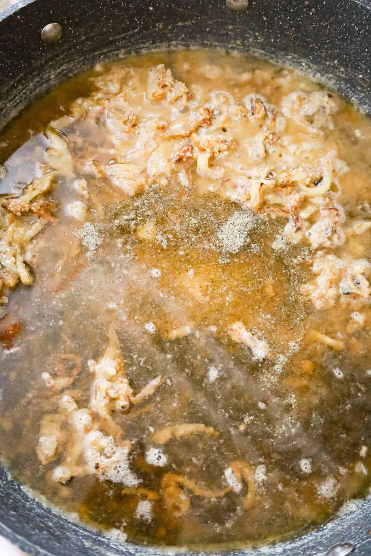 beef broth added to onions and flour mixture in a pan