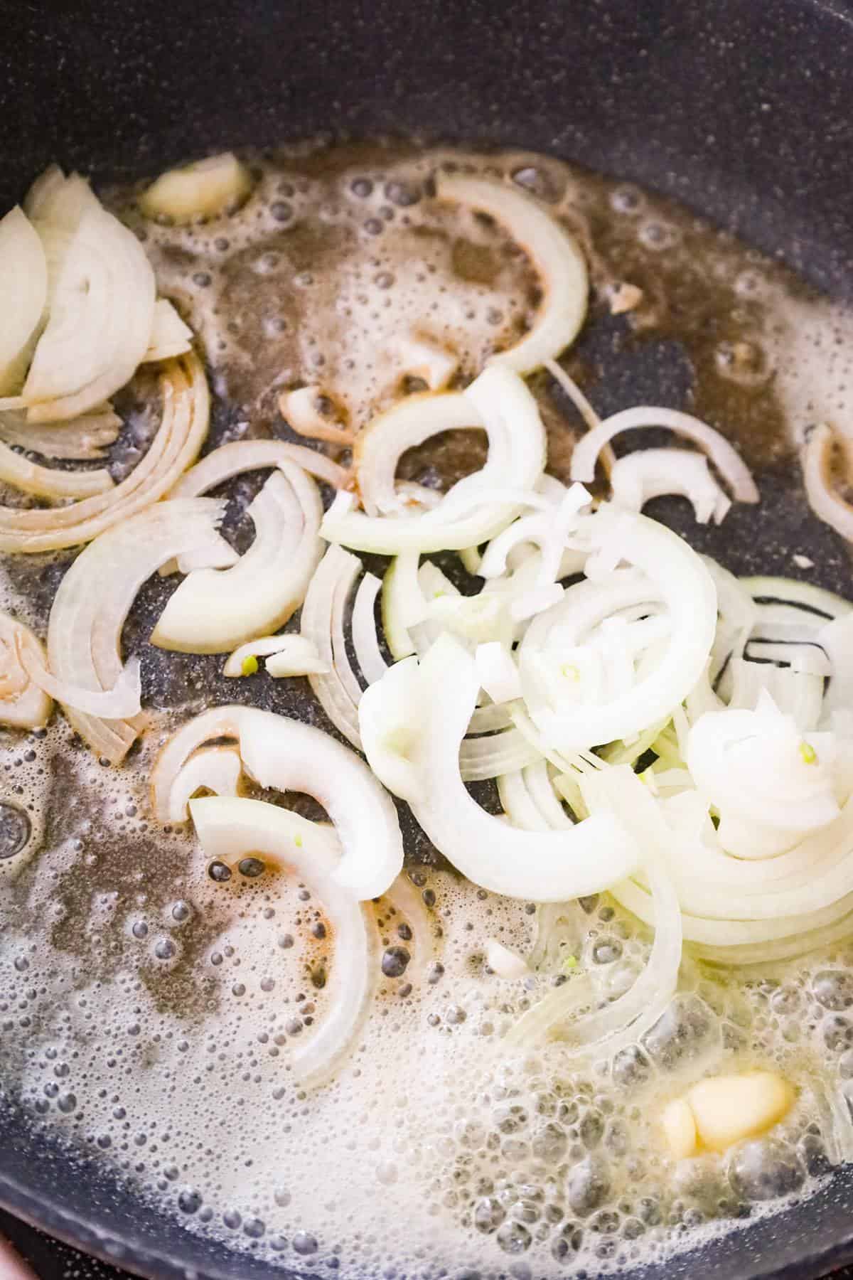sliced onions in a pan with melted butter