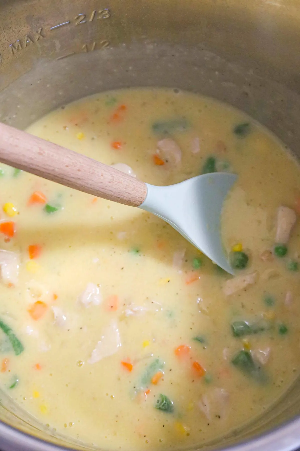 creamy chicken and vegetable mixture being stirred in an Instant Pot