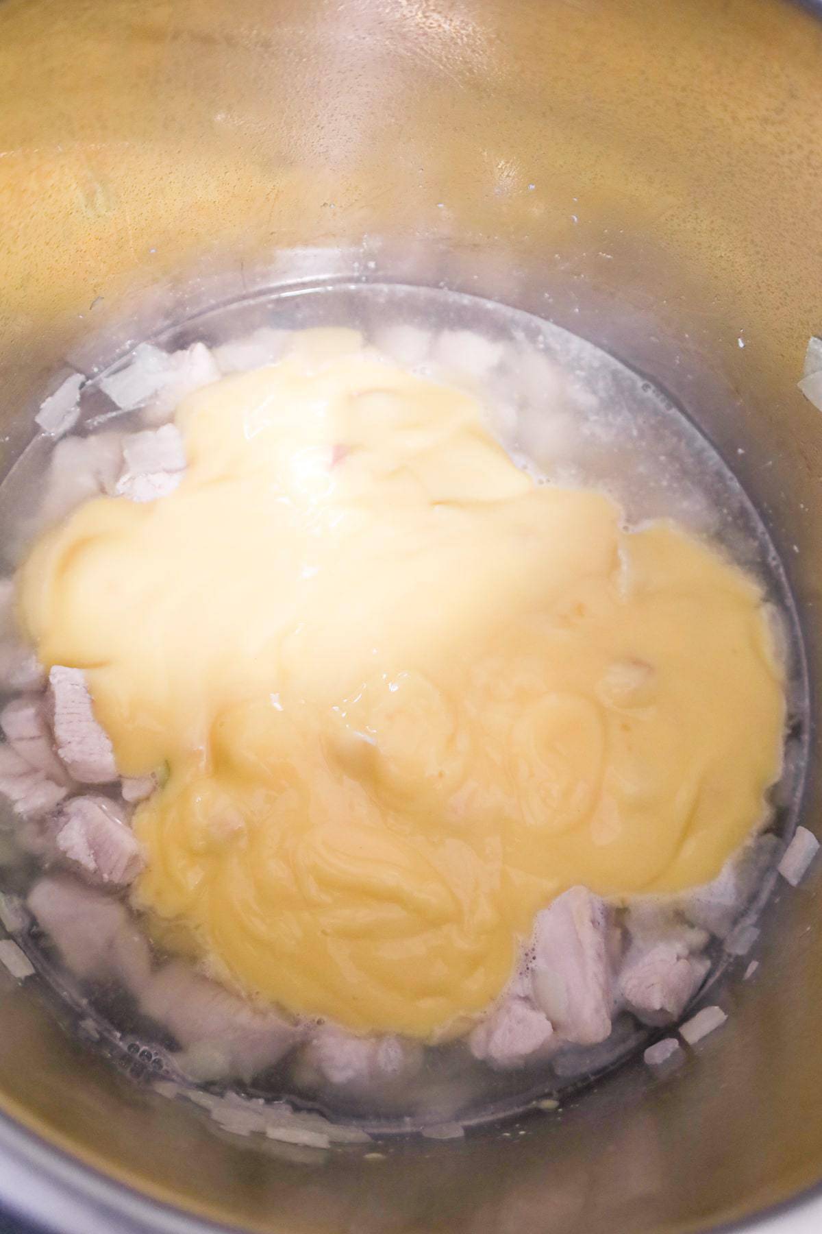 condensed cream of chicken soup on top of chicken chunks and water in an Instant Pot