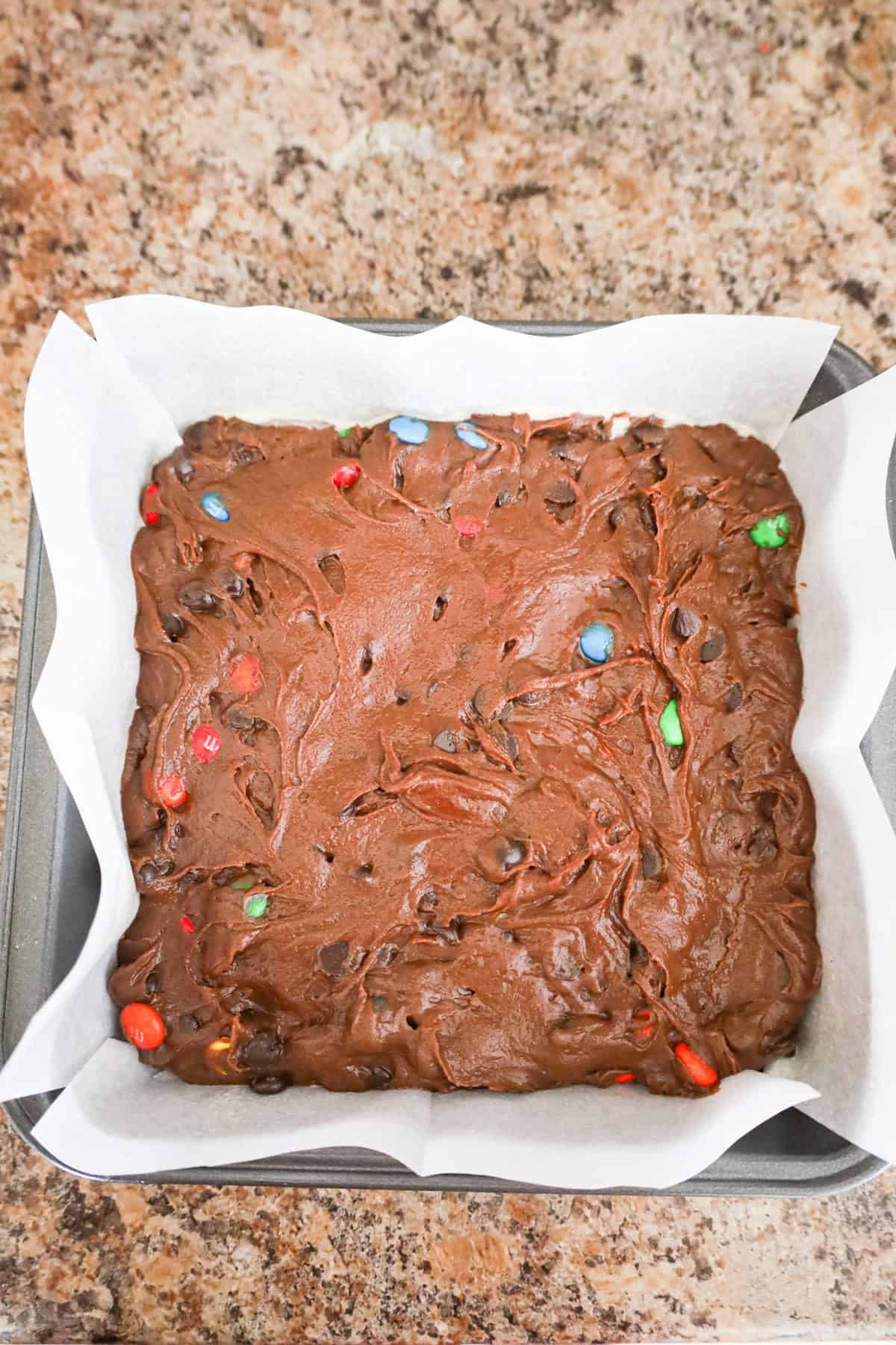 brownie batter in a parchment lined baking pan