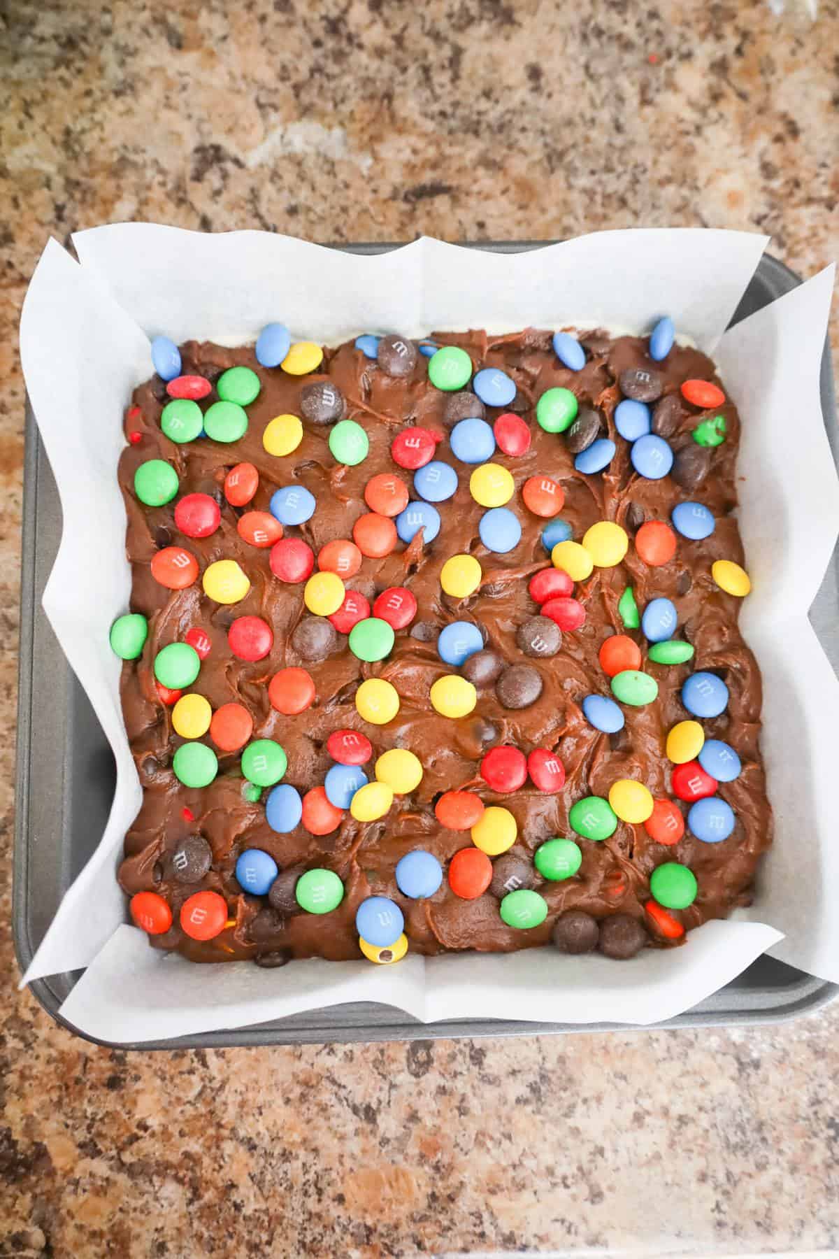 M&M brownie batter in a square baking pan