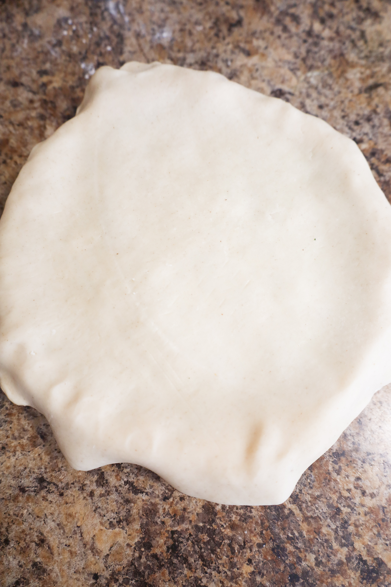 top pie crust hanging over sides of pie plate