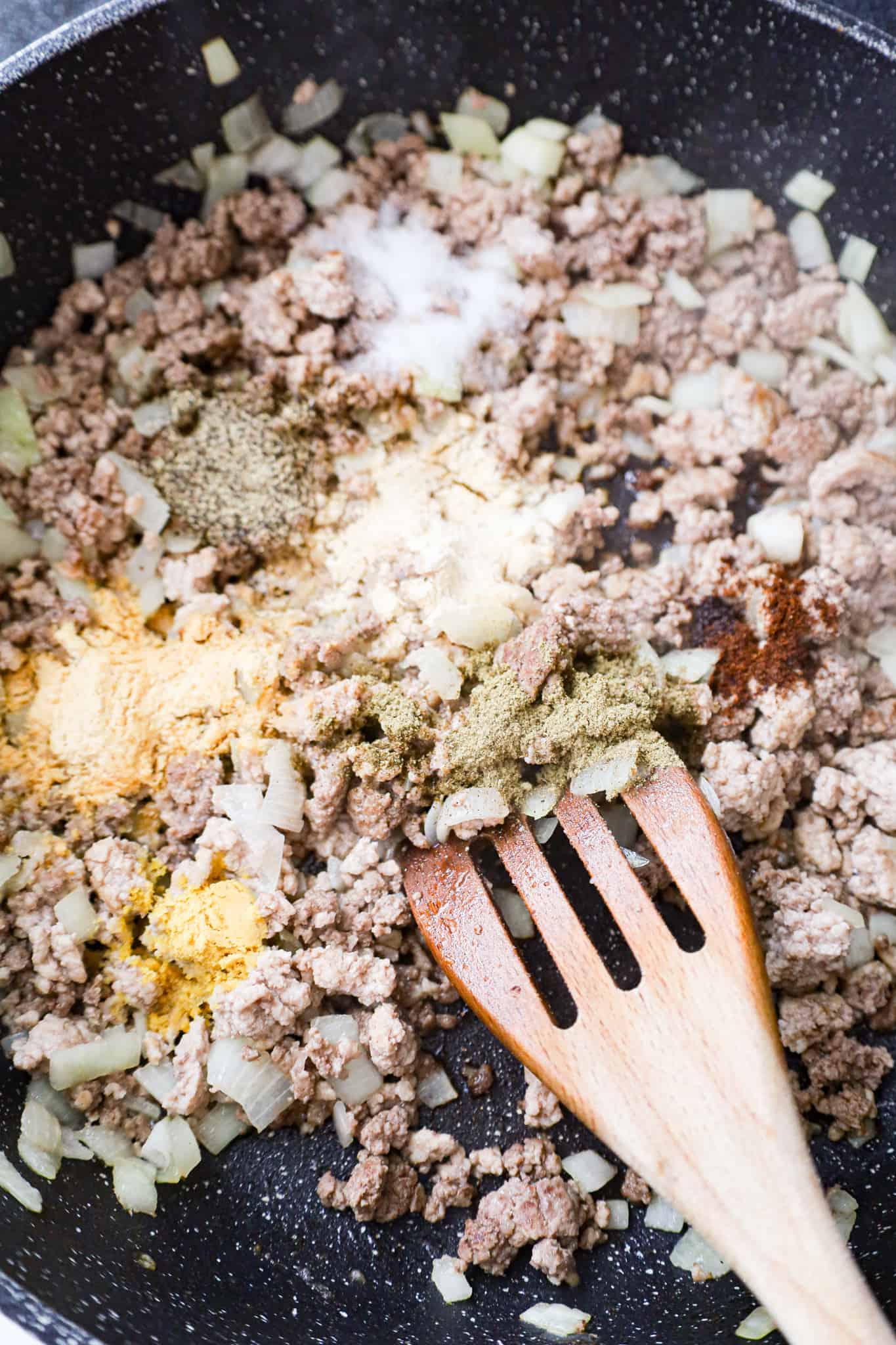 spices on top of cooked ground beef and ground pork in a saute pan