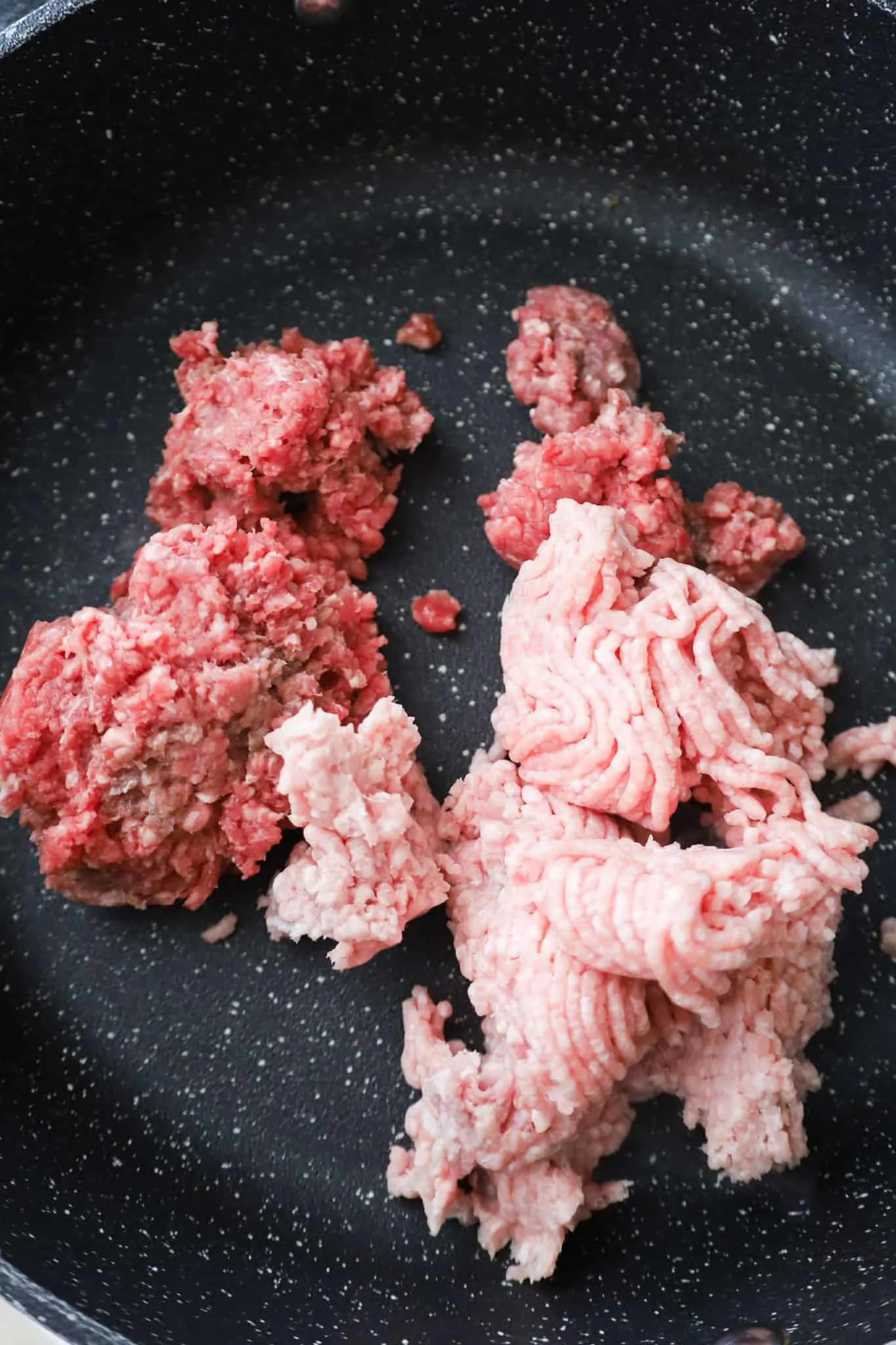raw ground beef and ground pork in a saute pan