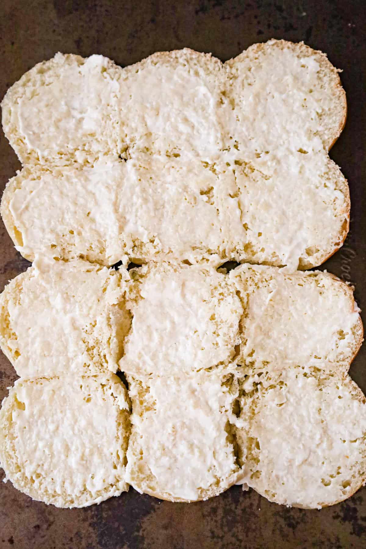 cut dinner rolls with mayo on a baking sheet