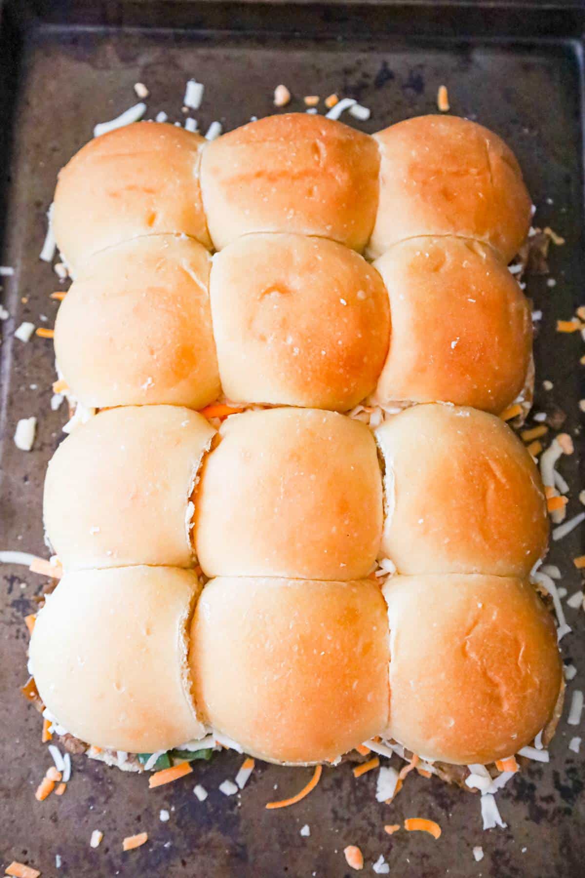 Philly cheese steak sliders on a baking sheet before baking