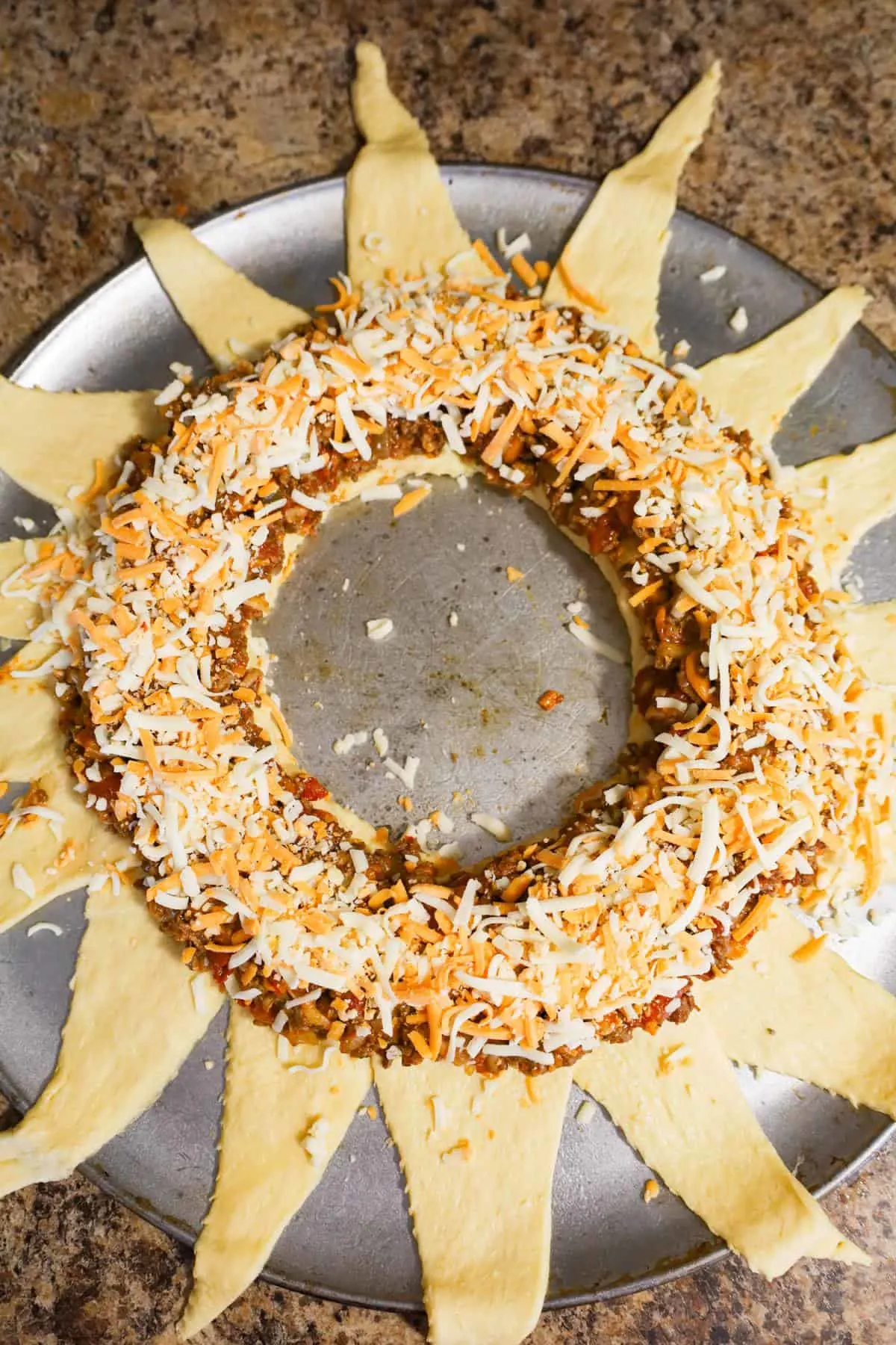 shredded cheese on top of ground beef mixture on crescent dough ring