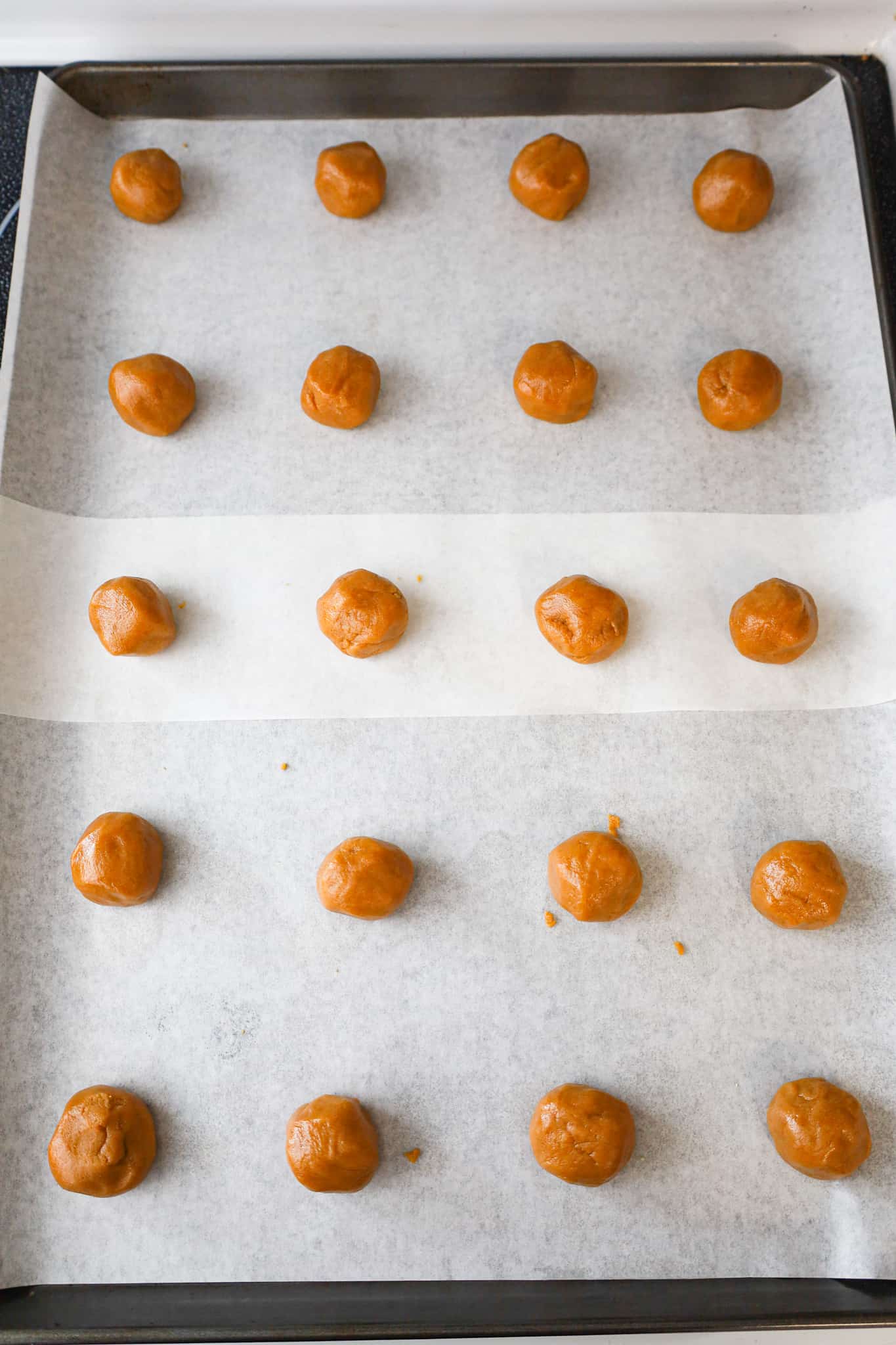 peanut butter cookie dough balls on a parchment lined baking sheet